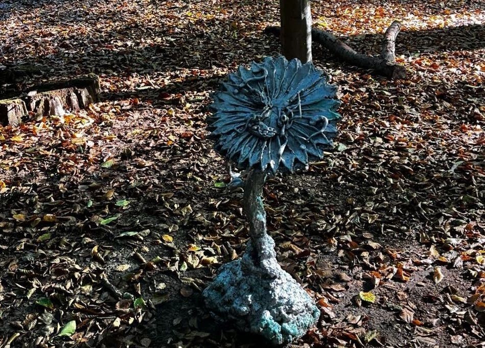 Artistic sculpture surrounded by autumn leaves near barbershop in Genk, Vlaanderen, BE.