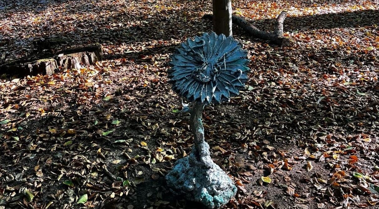Artistic sculpture surrounded by autumn leaves near barbershop in Genk, Vlaanderen, BE.