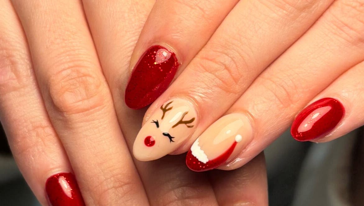 Diseño navideño de uñas en Beii Nails ✨💅🏼, Comunidad De Madrid, ES. Uñas rojas con reno y gorro navideño.