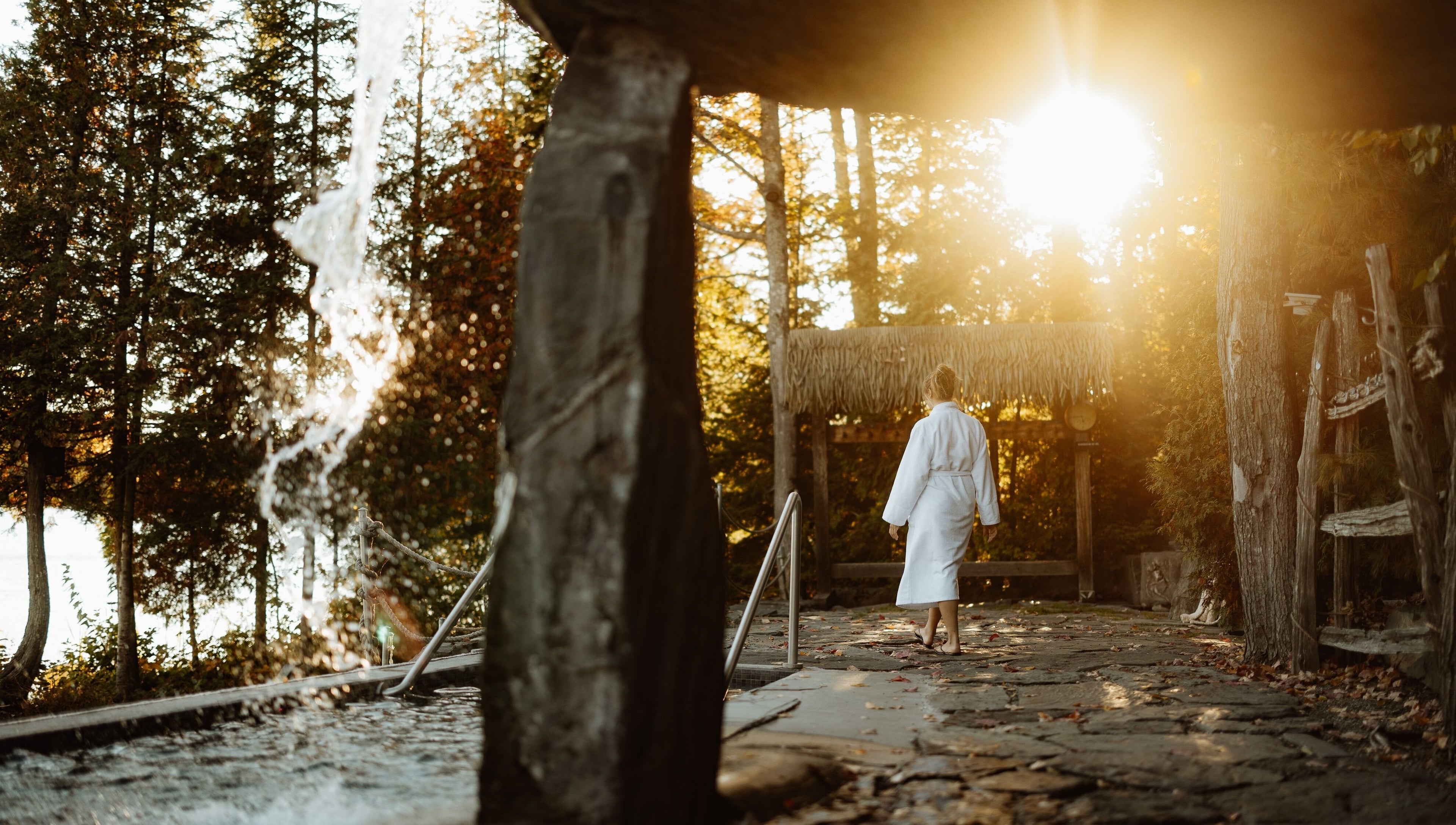 Femme en peignoir à Sartiga Spa sur le Lac, Saint-alfred, Québec, CA, entourée de nature et cascades.