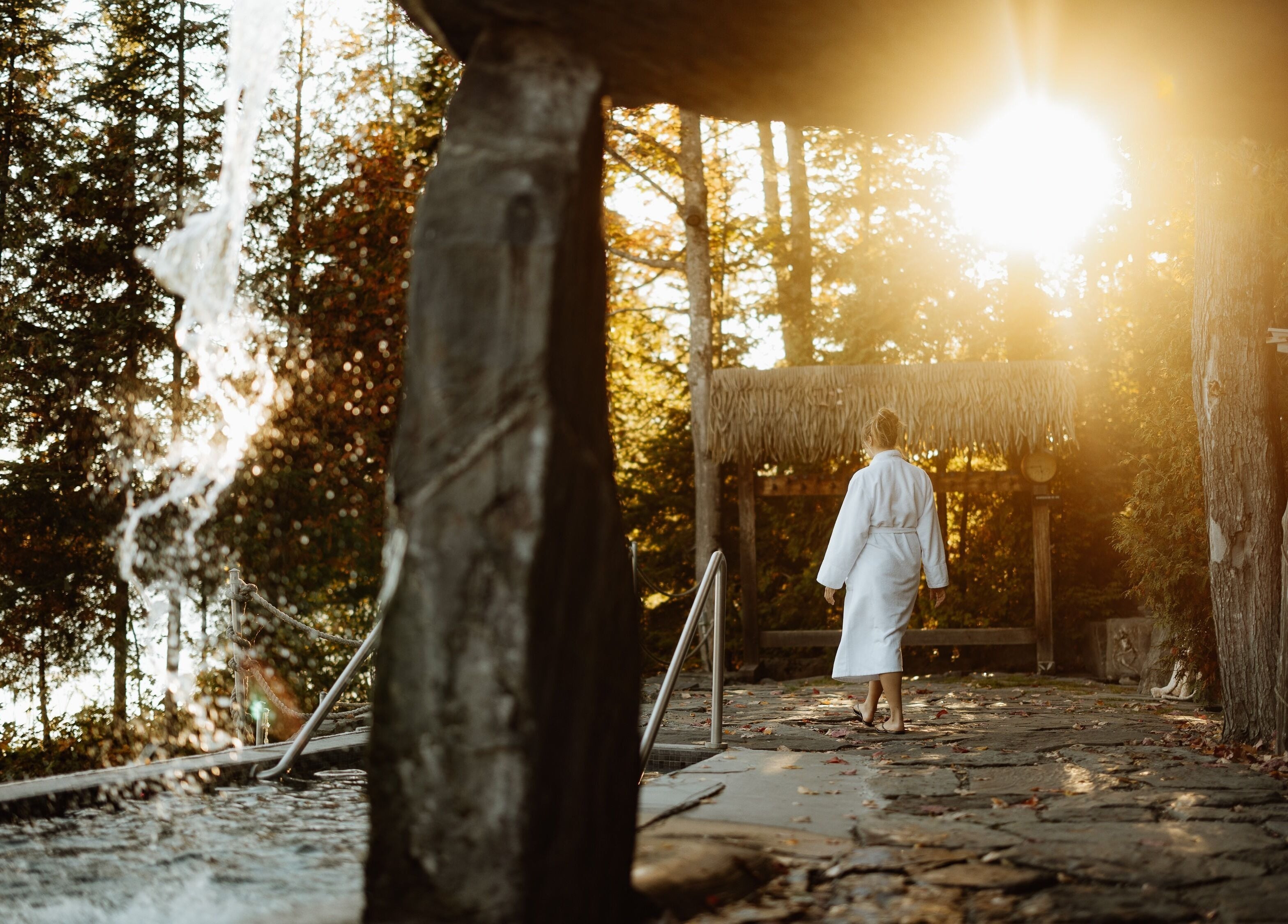 Femme en peignoir à Sartiga Spa sur le Lac, Saint-alfred, Québec, CA, entourée de nature et cascades.