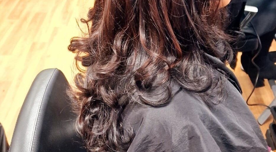 Elegant wavy hairstyle at Dan Hair Style in Birmingham, England, GB. Vibrant brown curls on a salon chair.