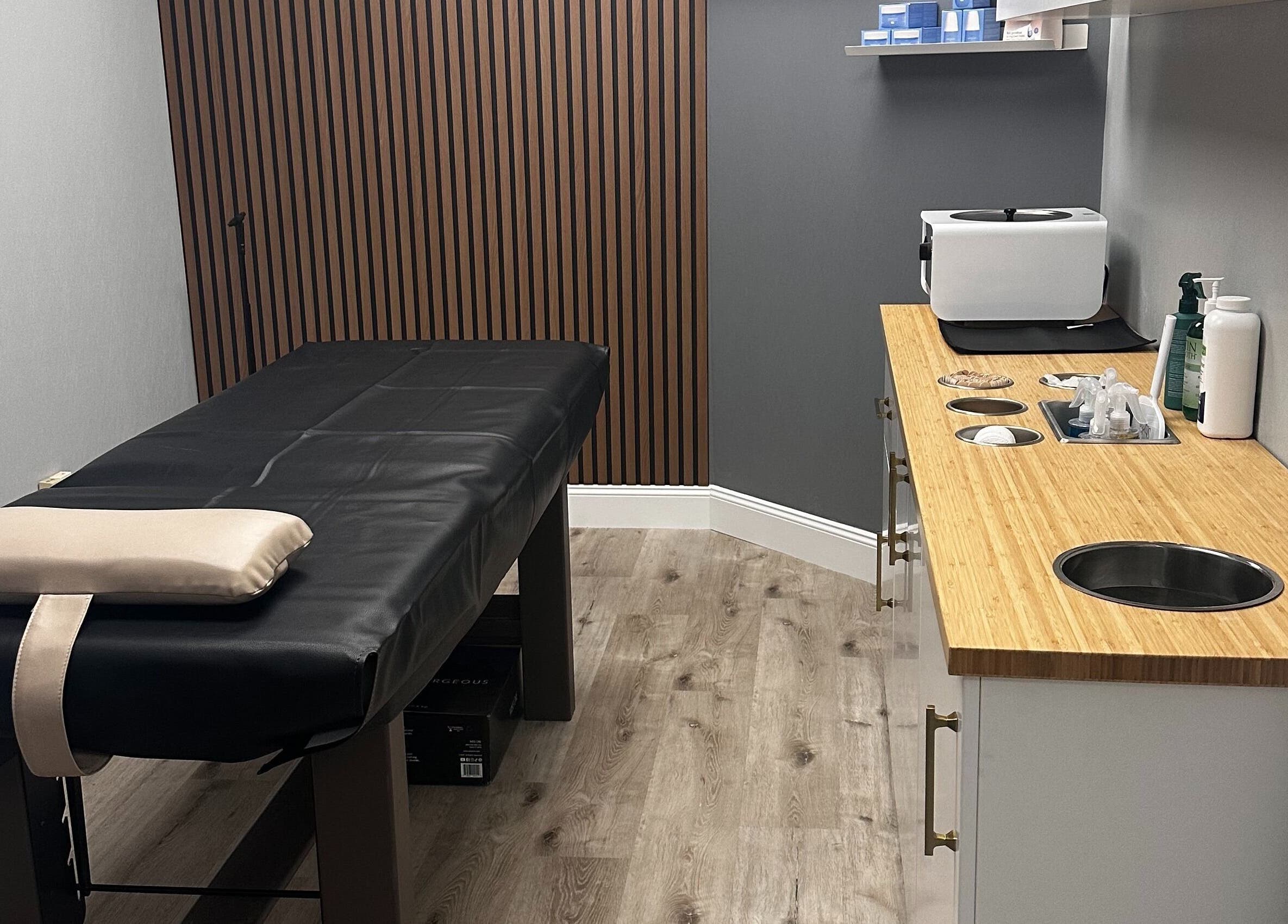 Cozy treatment room at Pro Wax Studio, Oradell, New Jersey, US, featuring a black massage table and supplies.
