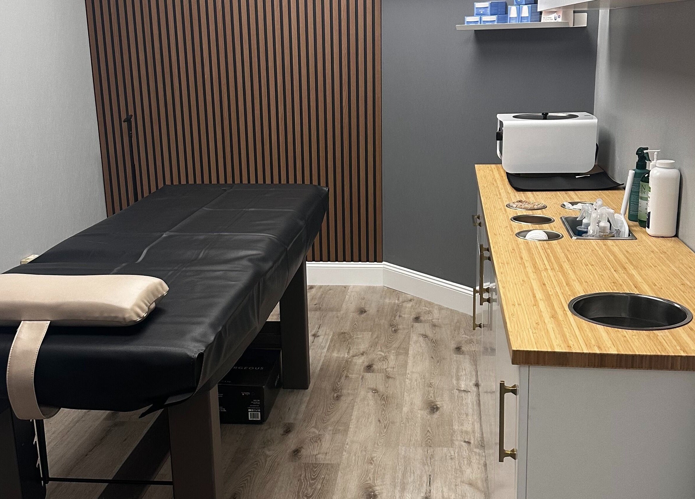 Cozy treatment room at Pro Wax Studio, Oradell, New Jersey, US, featuring a black massage table and supplies.