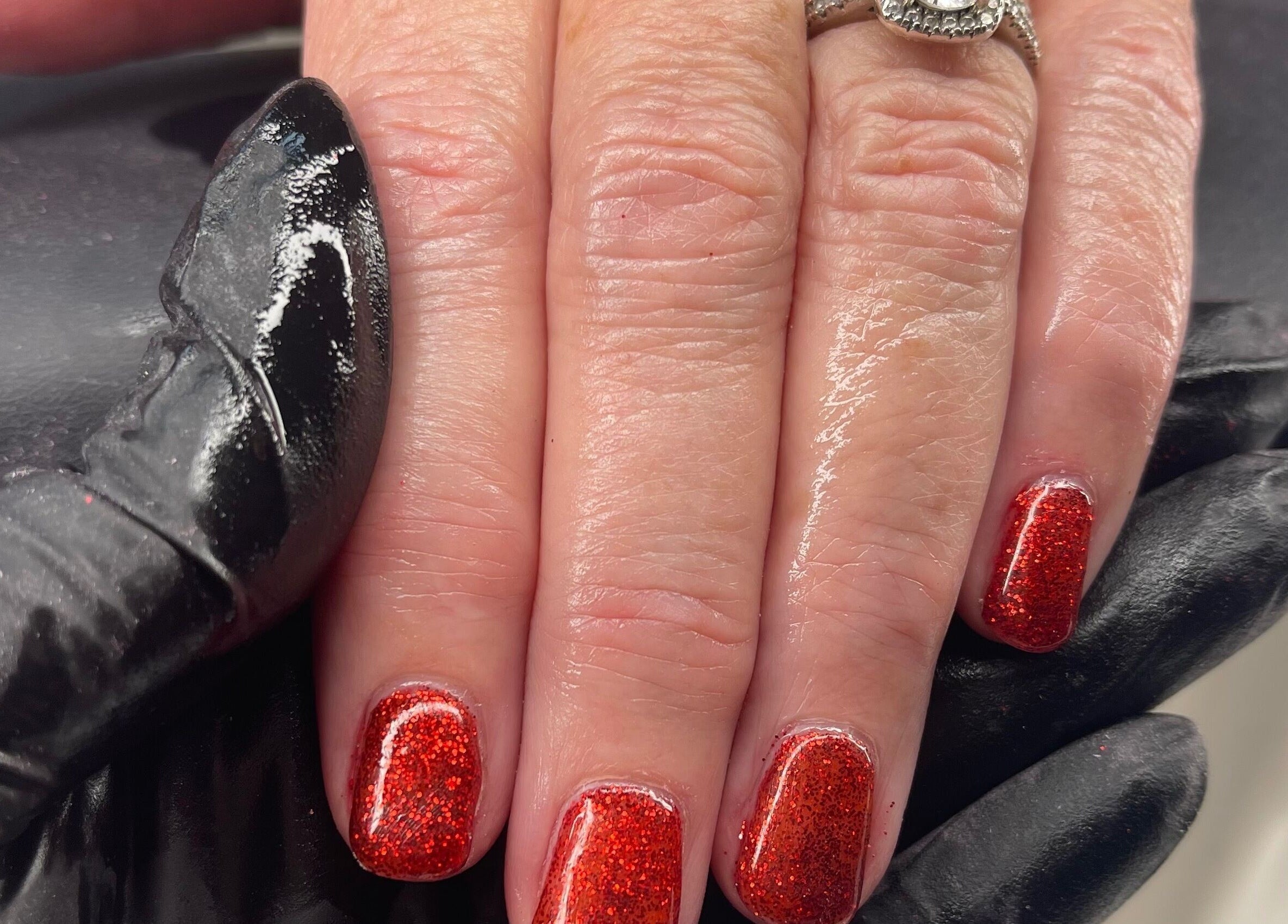 Glittery red manicure at Coco’s Beauty, Clanfield, England, GB showcasing intricate nail art details.