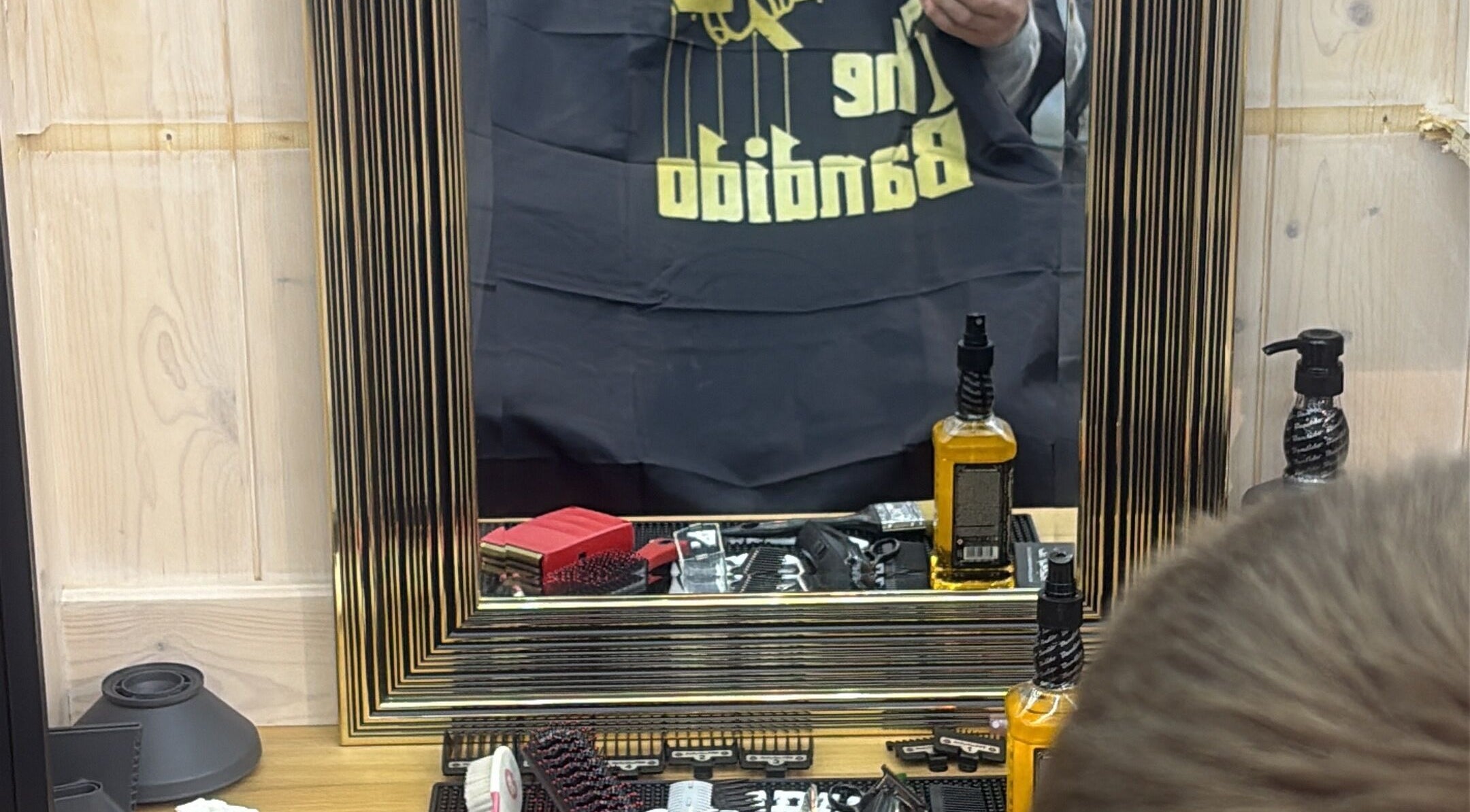 Интерьер Barbershop в Heist, Vlaanderen, BE с продуктами для ухода и аксессуарами на столе.