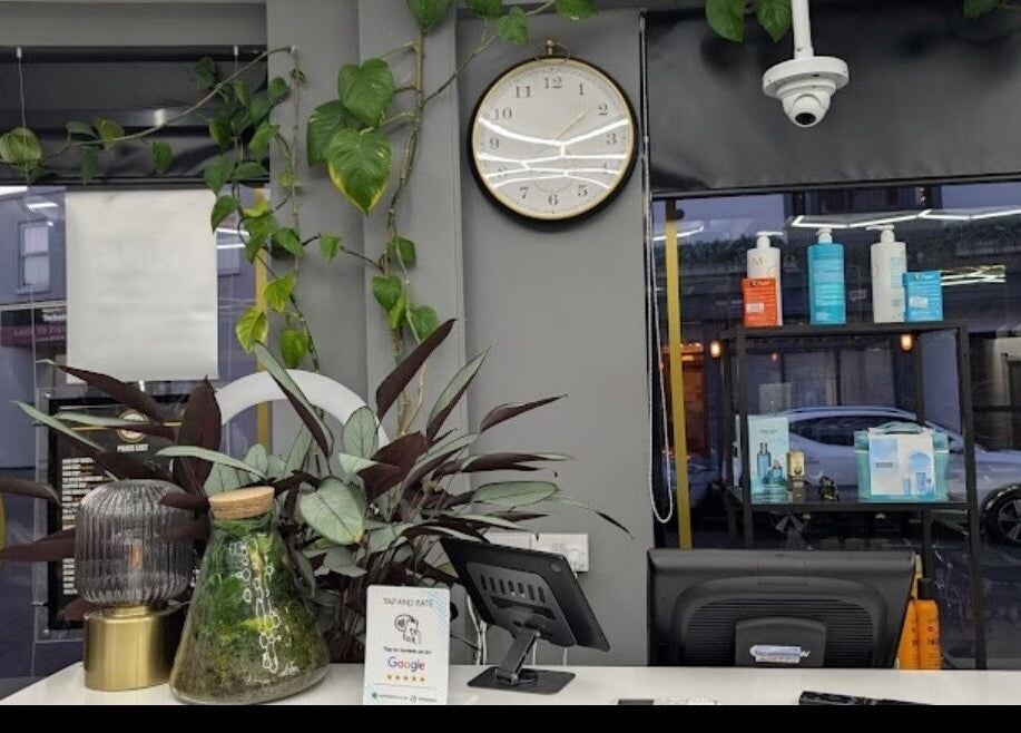 Reception area of Turkish Barber, Birmingham, England, GB with plants and clock.