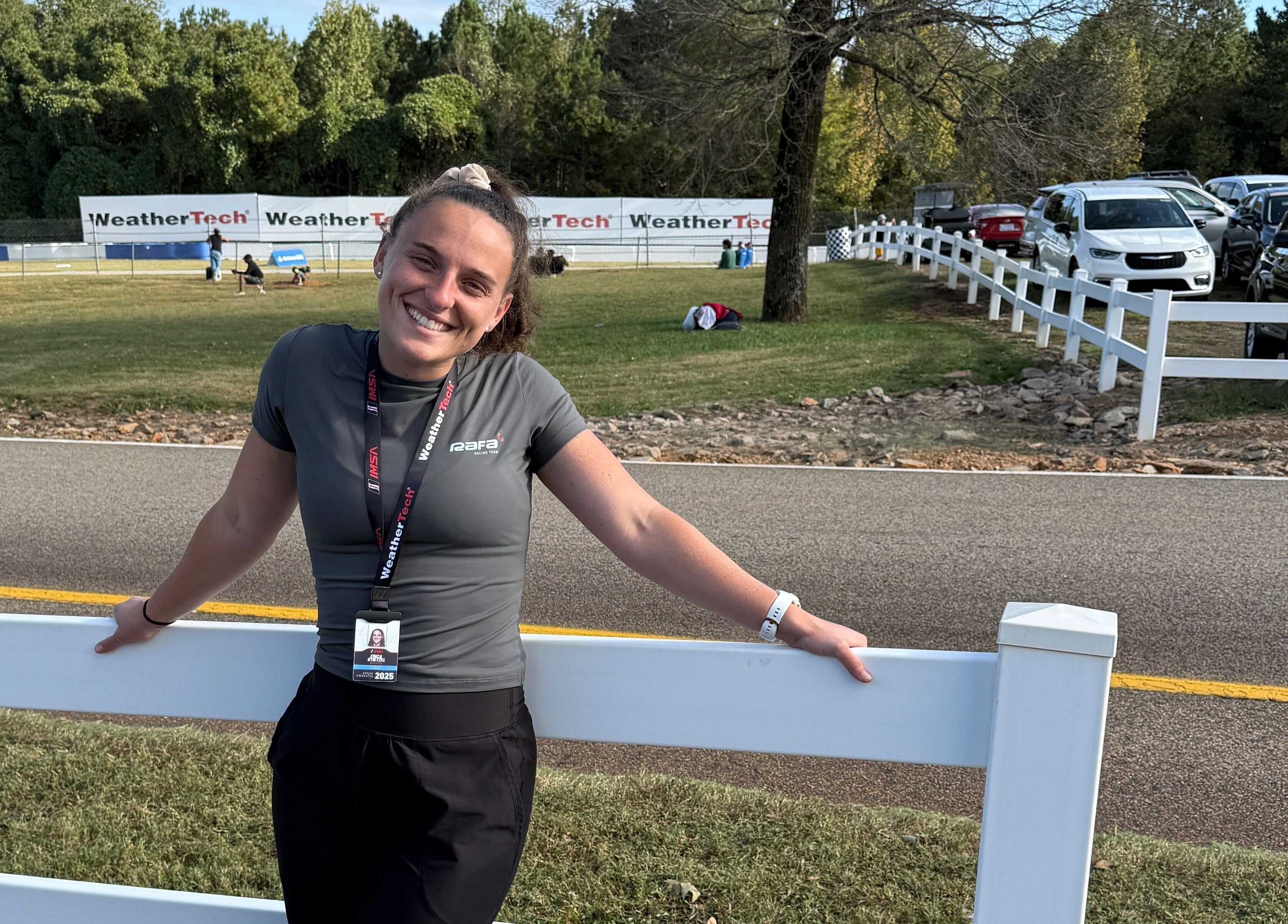 Woman smiling by fence at Strides Performance in Stamford, Connecticut, US, under blue sky.