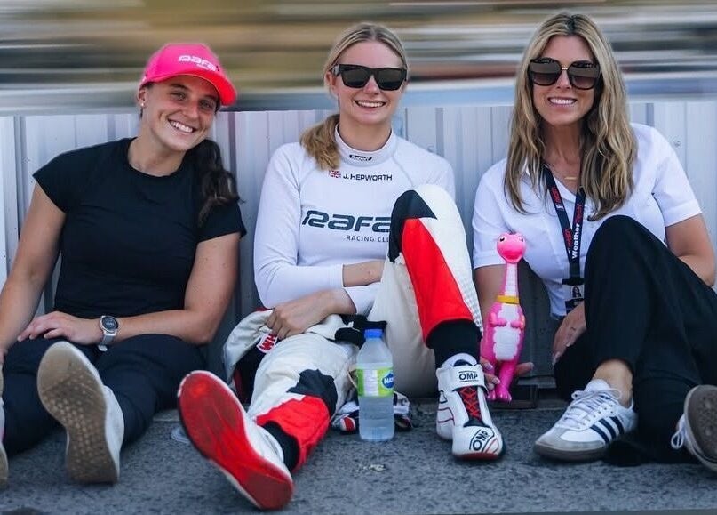 Three women relaxing at a racing event, embodying casual style near Strides Performance, Stamford, Connecticut, US.