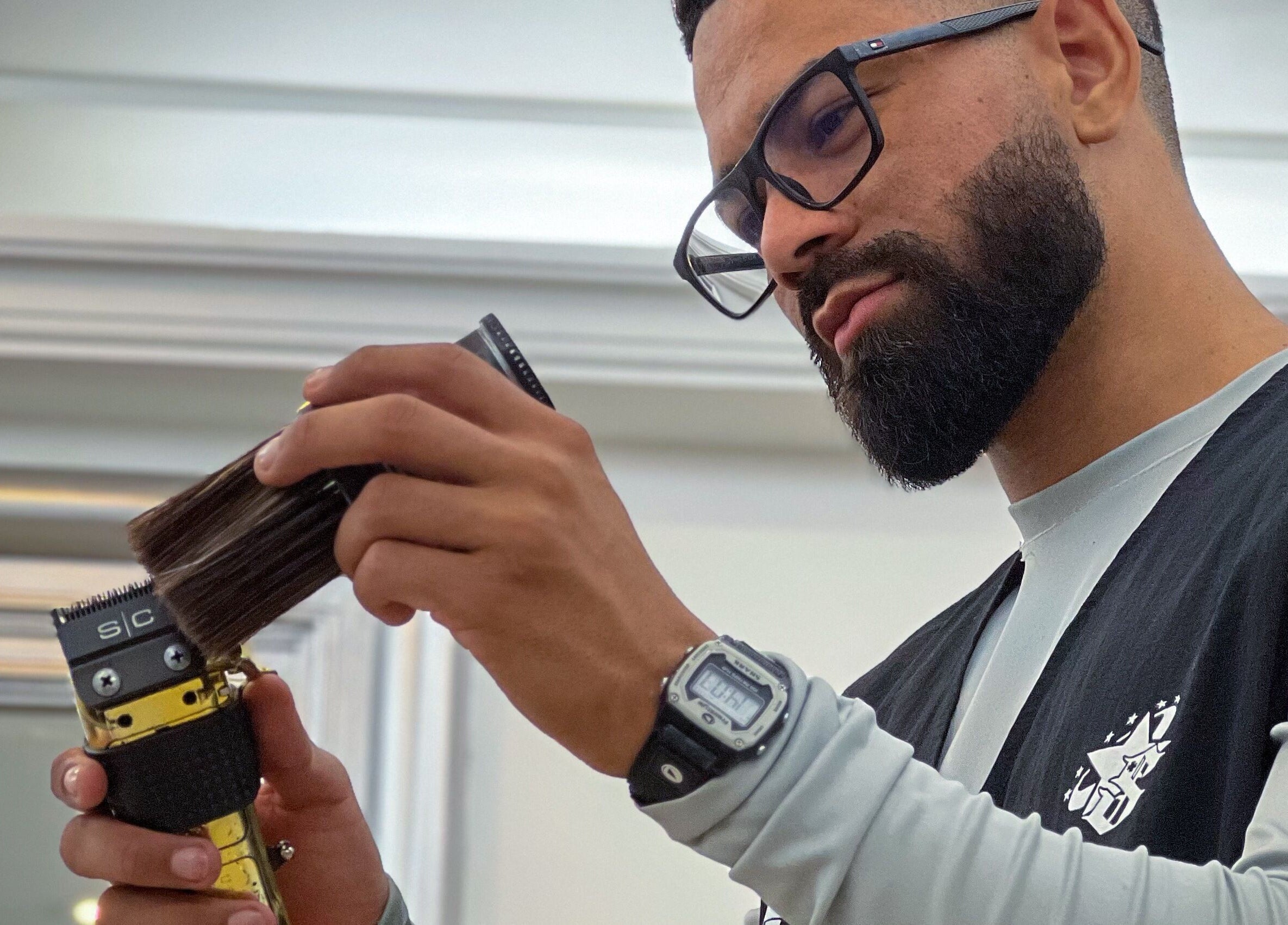 Barbero concentrado en Gerzon barber, Maiquetía, La Guaira, VE usando una herramienta de corte.