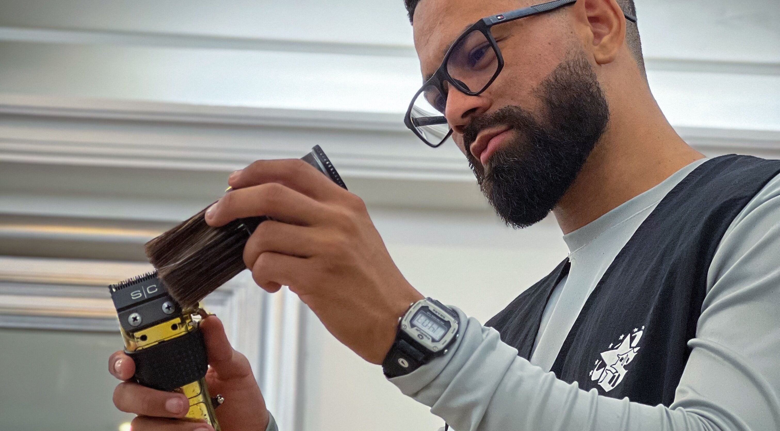 Barbero concentrado en Gerzon barber, Maiquetía, La Guaira, VE usando una herramienta de corte.