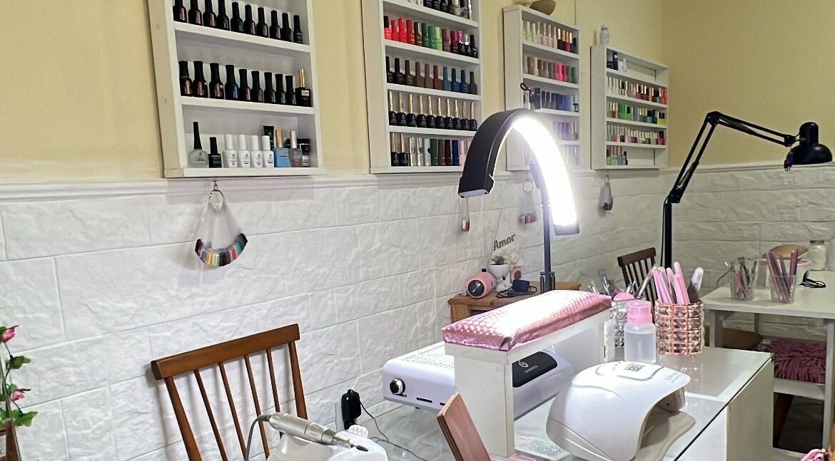 Mesa de manicura en Nails by Guada, Villa Vatteone, Provincia De Buenos Aires, AR, con estantes llenos de esmaltes.