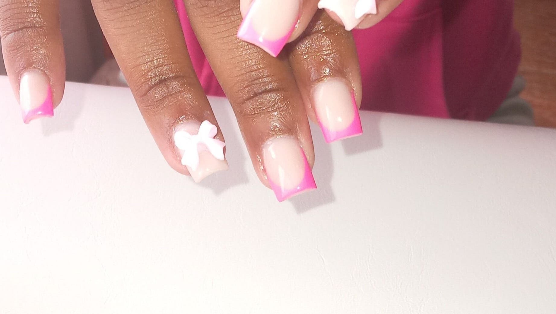 Vibrant pink nail art with white bow at ZEE.NAILS, Sebokeng, Gauteng, ZA, showcasing creative designs.