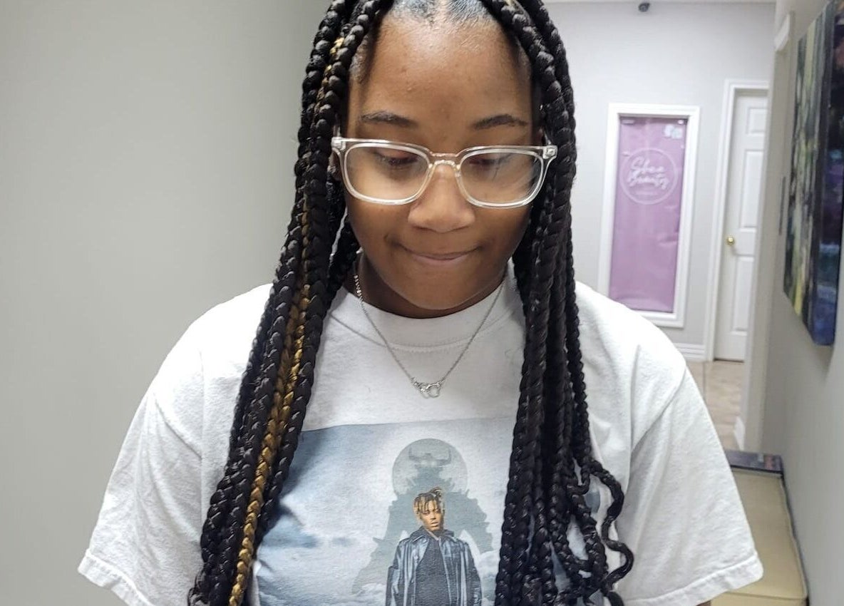 Client avec des tresses longues à Fef Hair Braiding Salon, Euless, Texas, US, montrant un style moderne.