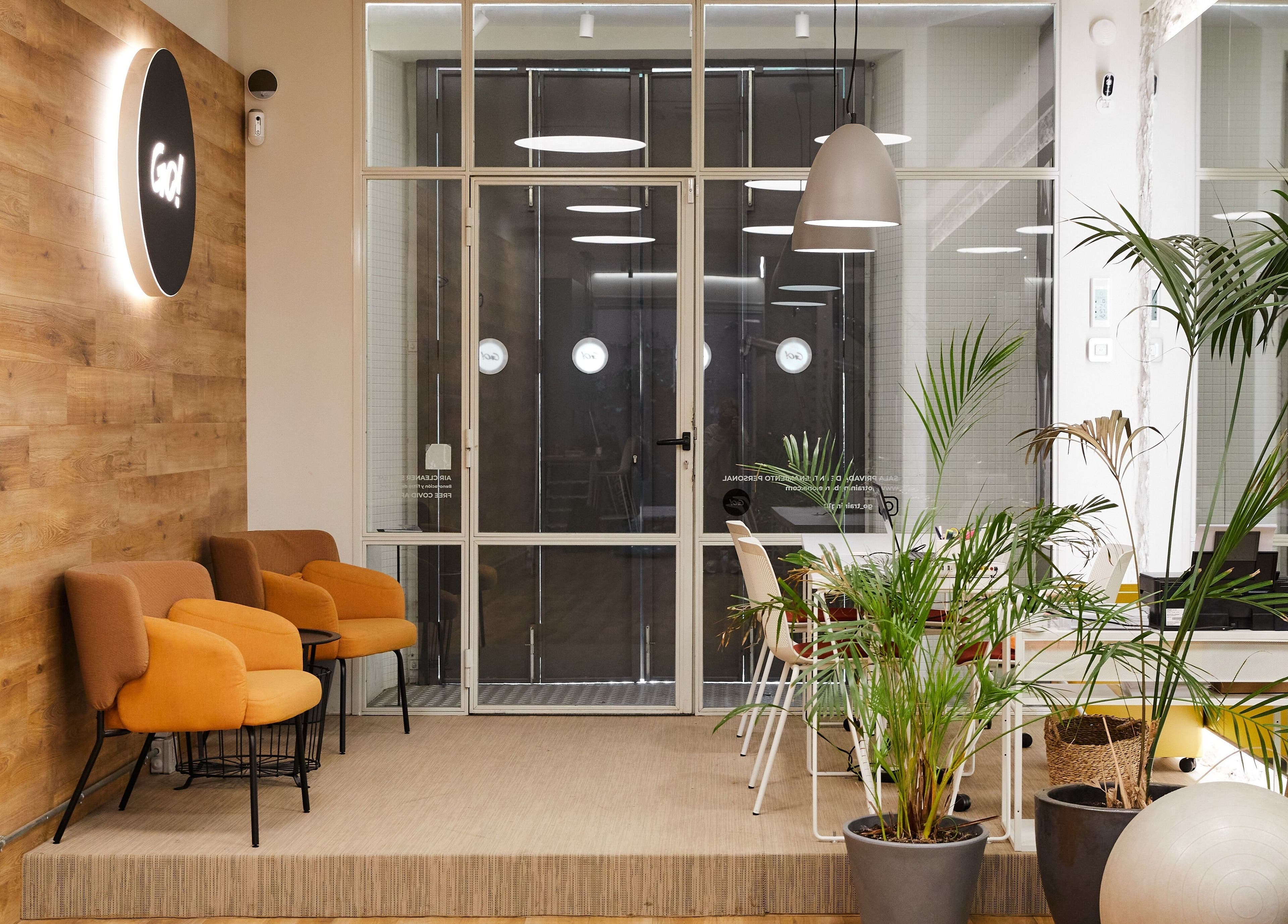 Zona de espera acogedora en Go Training Barcelona, con sillas naranjas y plantas. Ubicado en Barcelona, Catalunya, ES.