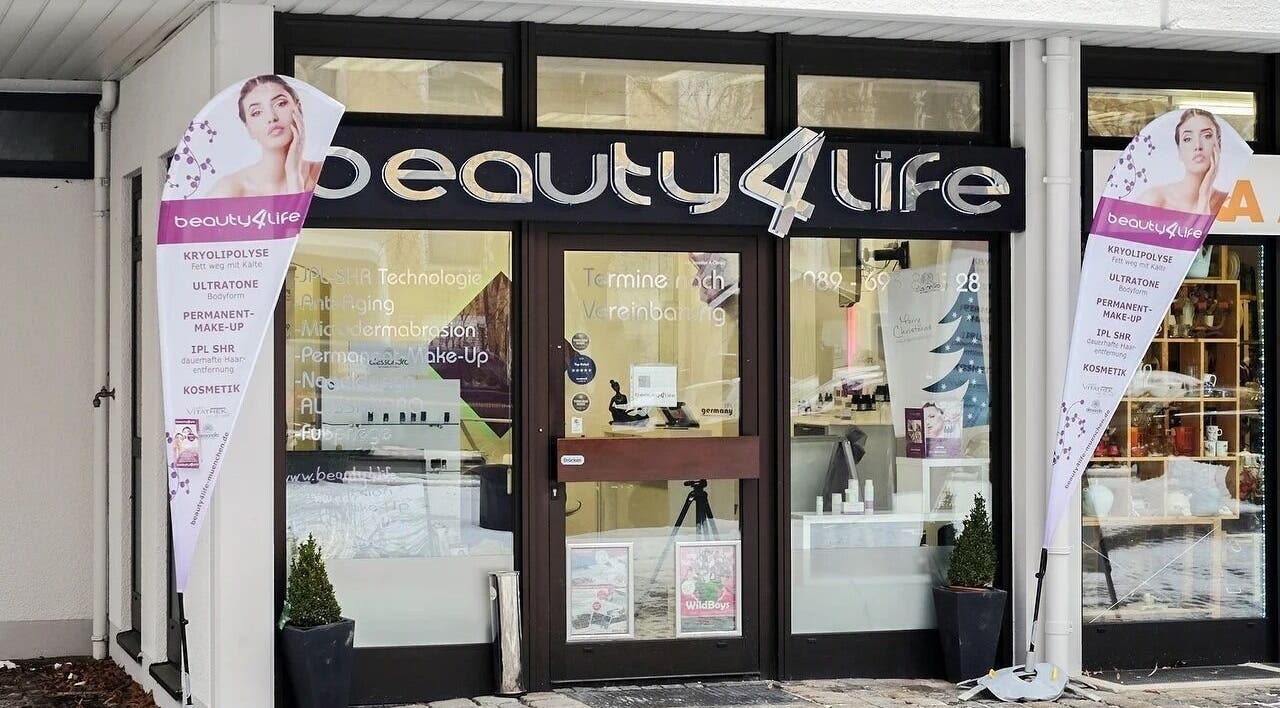 Eingang von Beauty4Life in München, Bayern, DE, mit Werbeschildern und moderner Glasfassade.