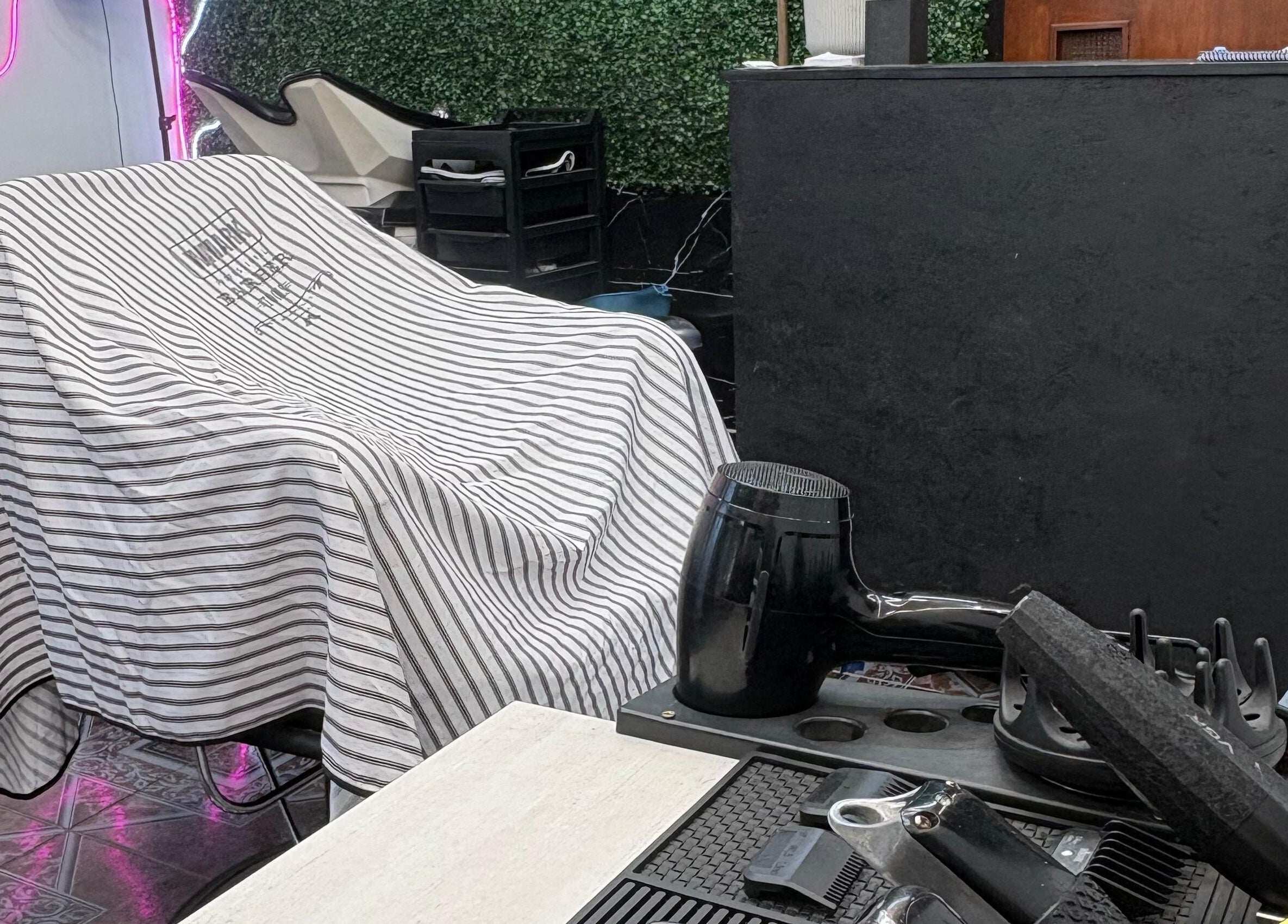 Zona de estilista en Navaja Dorada, Córdoba, Córdoba, AR con secador y silla cubierta.