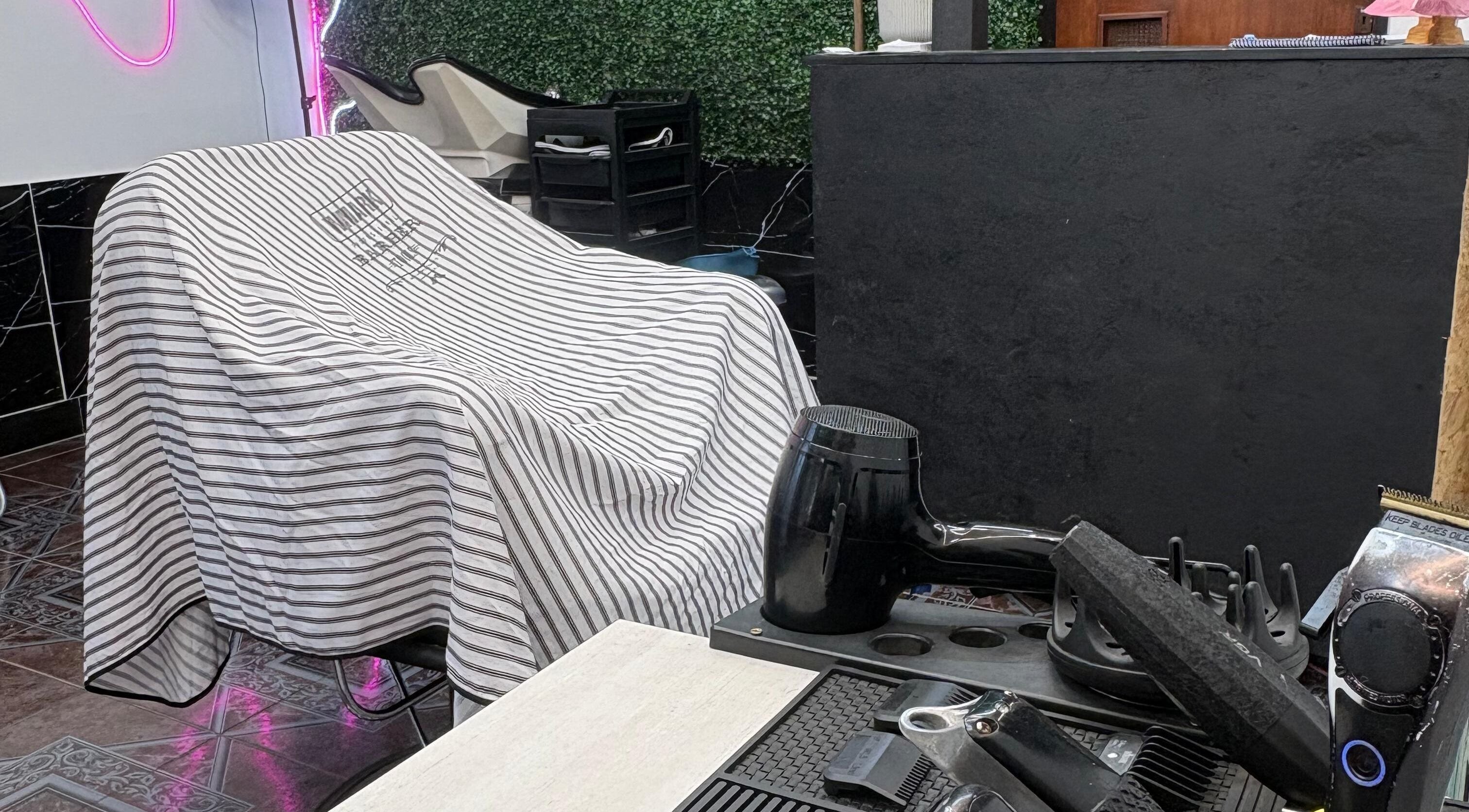 Zona de estilista en Navaja Dorada, Córdoba, Córdoba, AR con secador y silla cubierta.