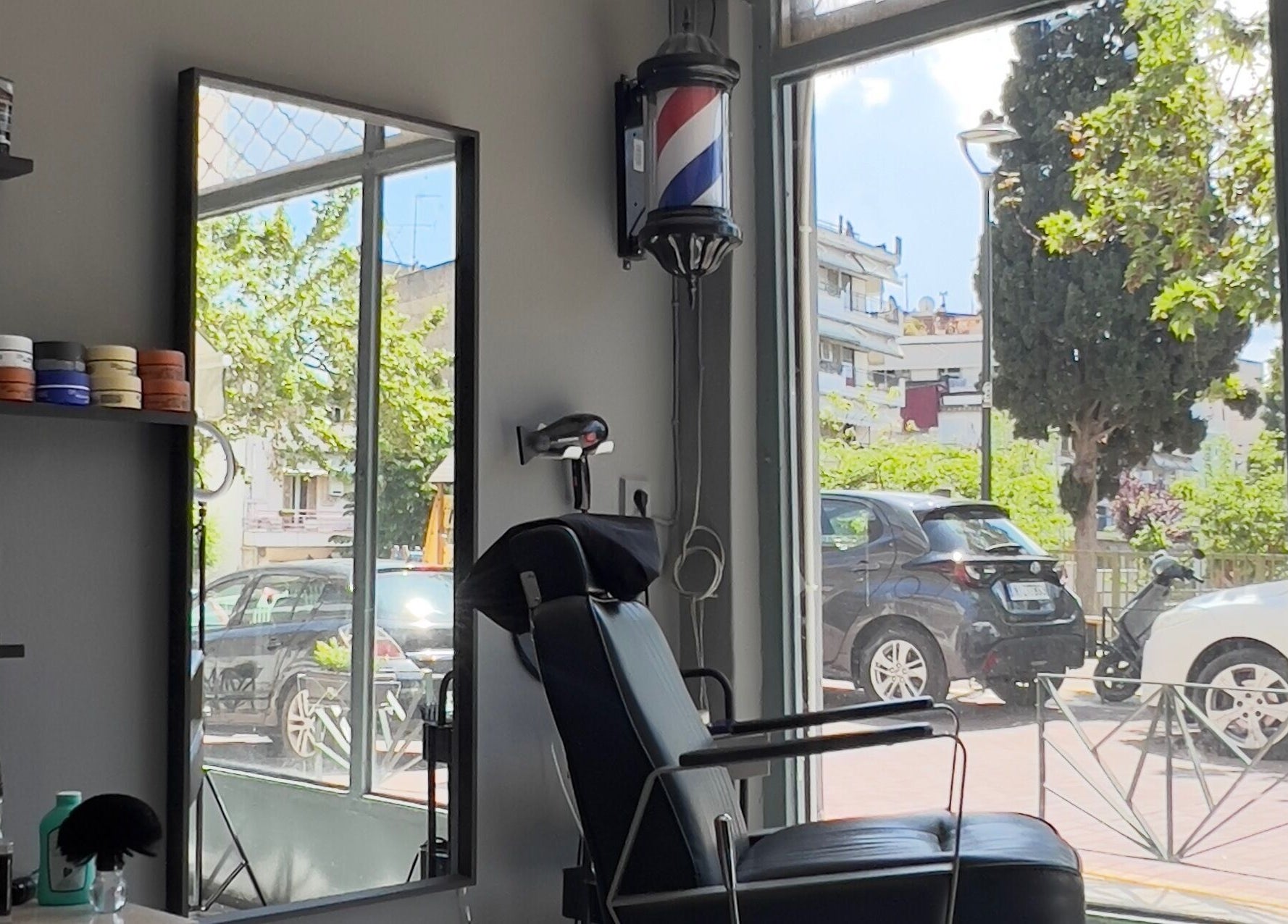 Inside NALDO HAIR STUDIO Neapoli, GR with chair and street view through large windows.