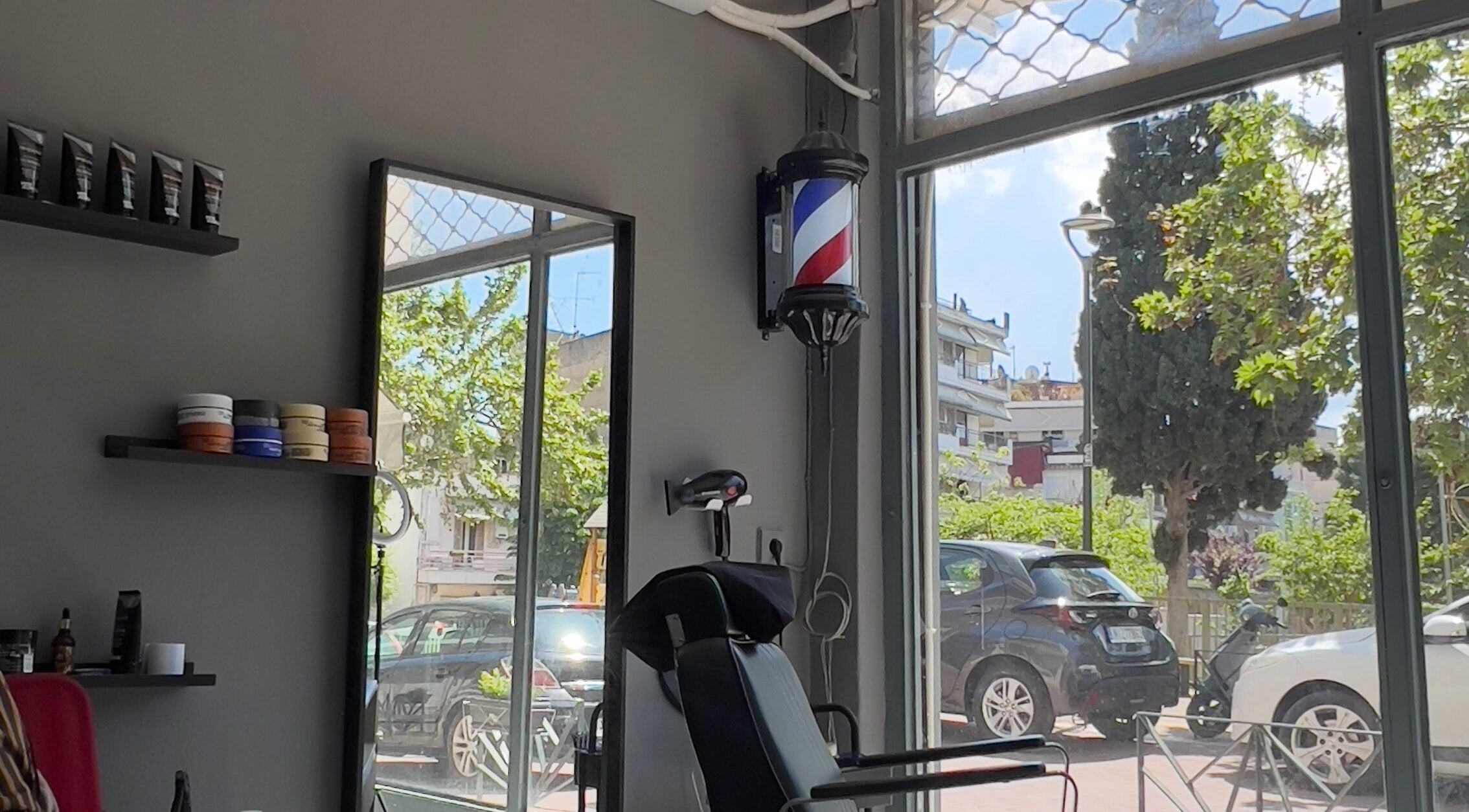 Interior of NALDO HAIR STUDIO in Neapoli, GR showcasing modern salon chair and hair products.