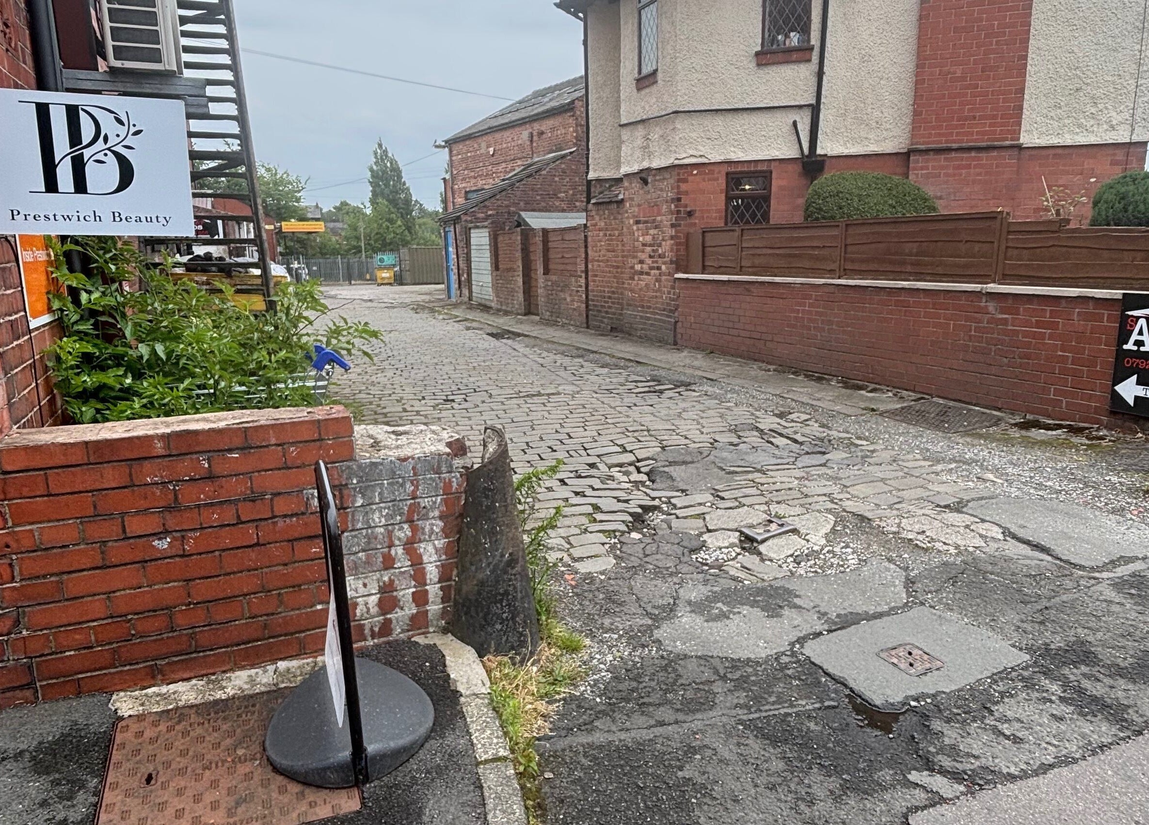 Entrance to Ej beauty service at Prestwich, England, GB, showing charming cobblestone street and brick architecture.
