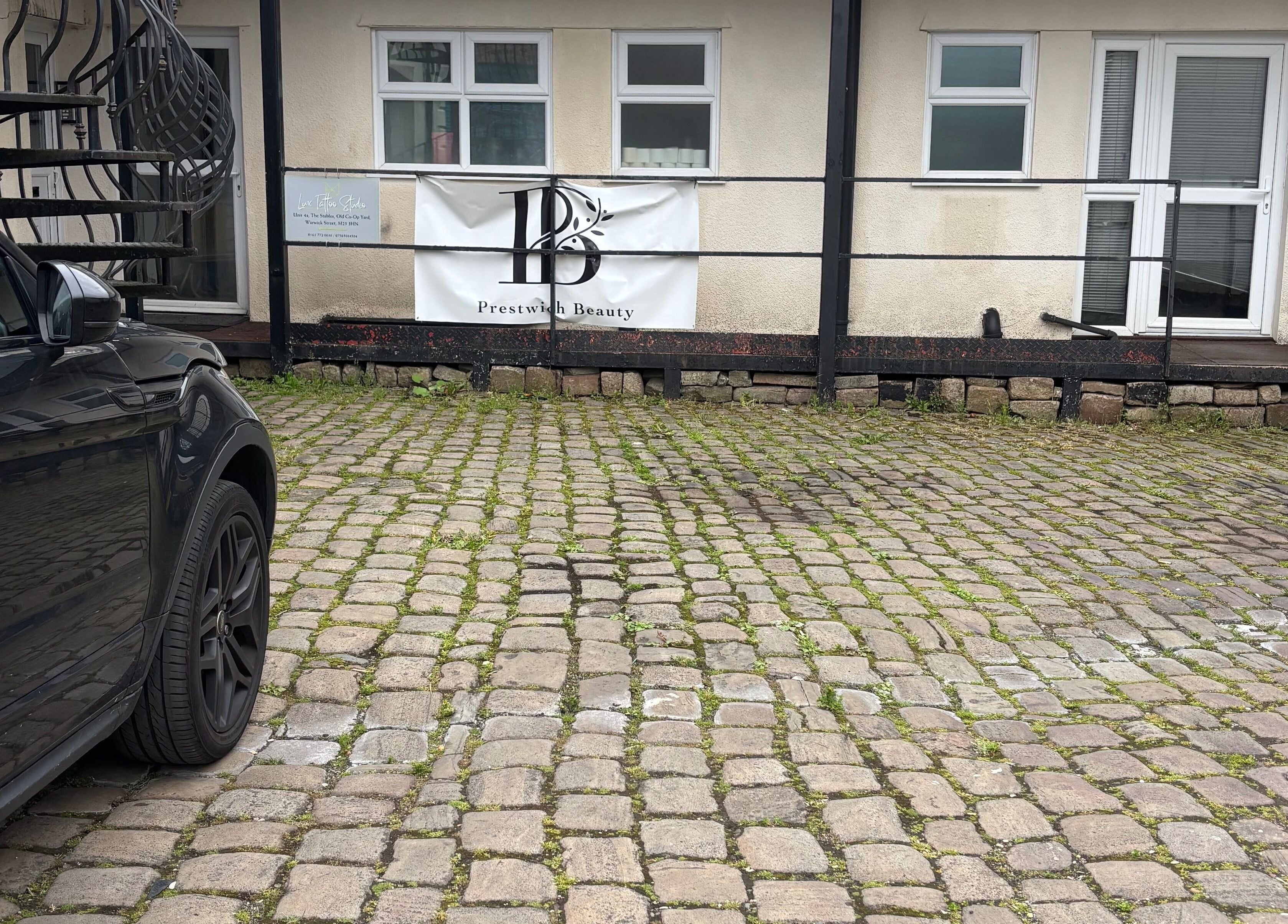 Exterior of Ej beauty service in Prestwich, England, GB, featuring cobblestone courtyard and entrance.