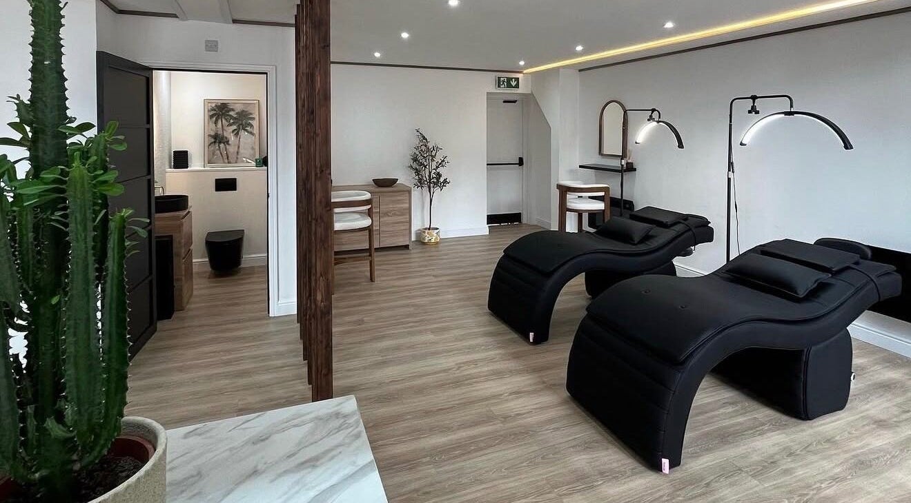 Modern wellness interior at Signature Brows CO, Flint, Wales, GB featuring sleek black loungers and minimalist decor.