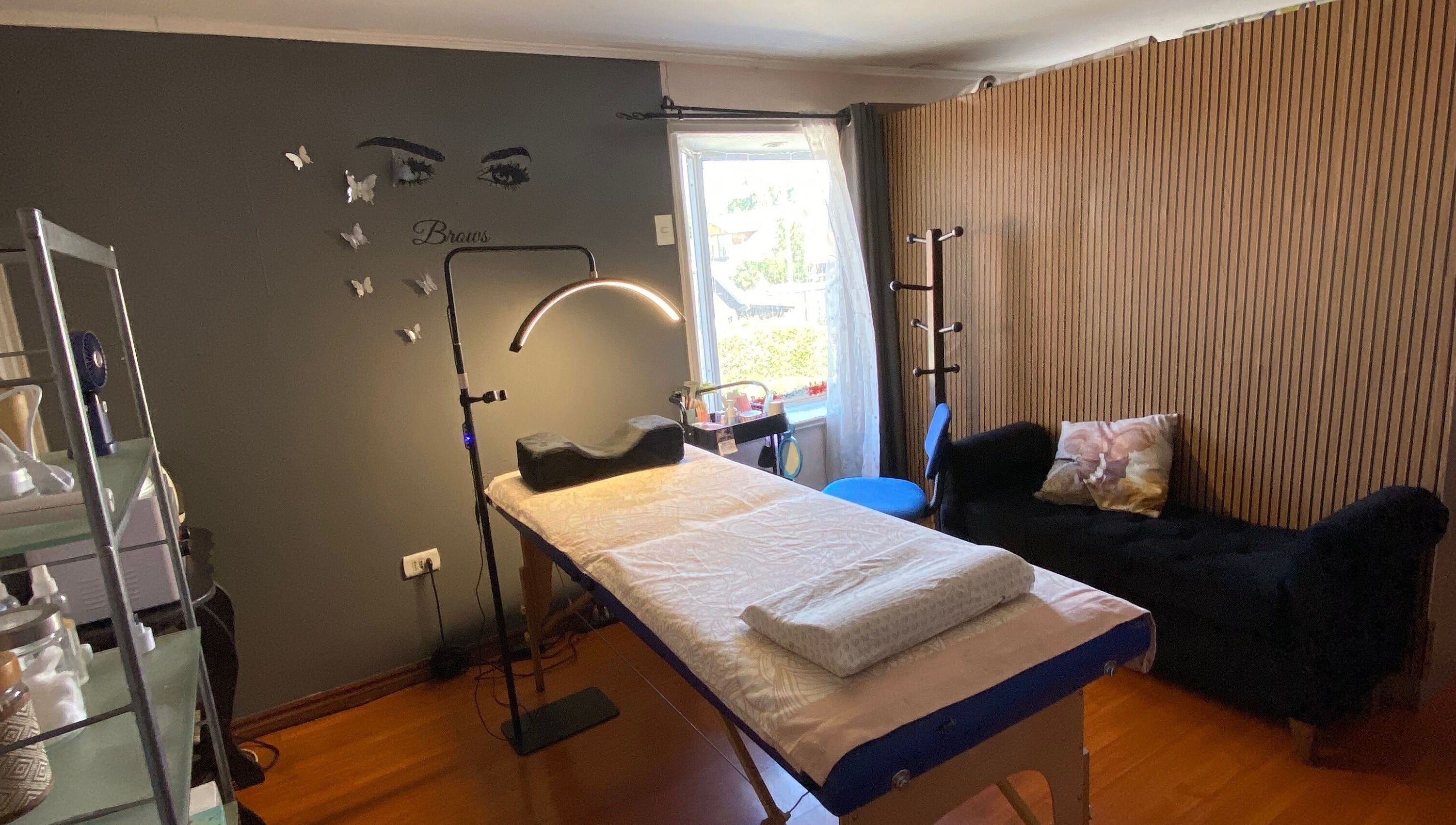 Interior acogedor del Centro estético Elyta’S, Región Metropolitana, CL. Sala con cama de tratamiento y decoraciones.