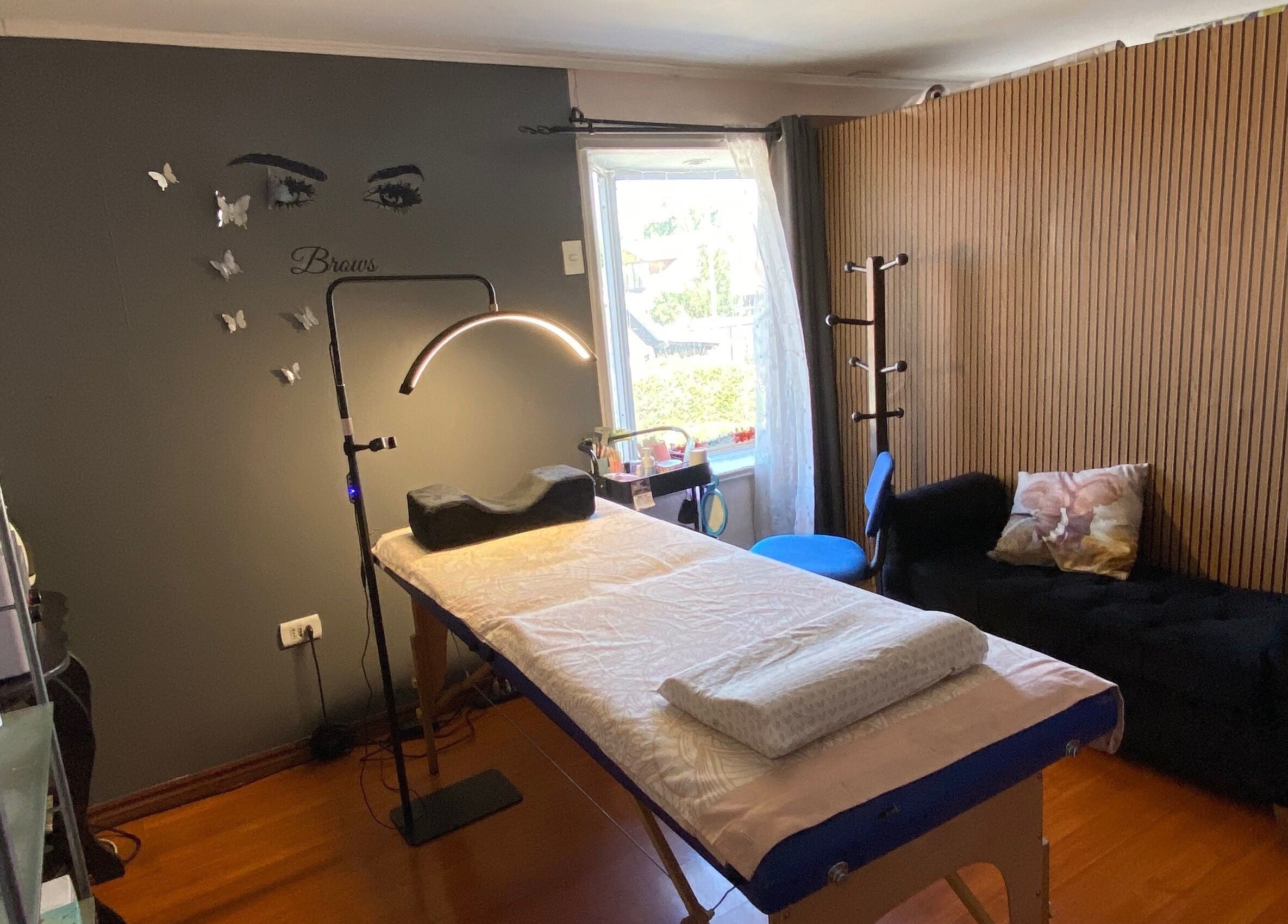 Interior acogedor del Centro estético Elyta’S, Región Metropolitana, CL. Sala con cama de tratamiento y decoraciones.