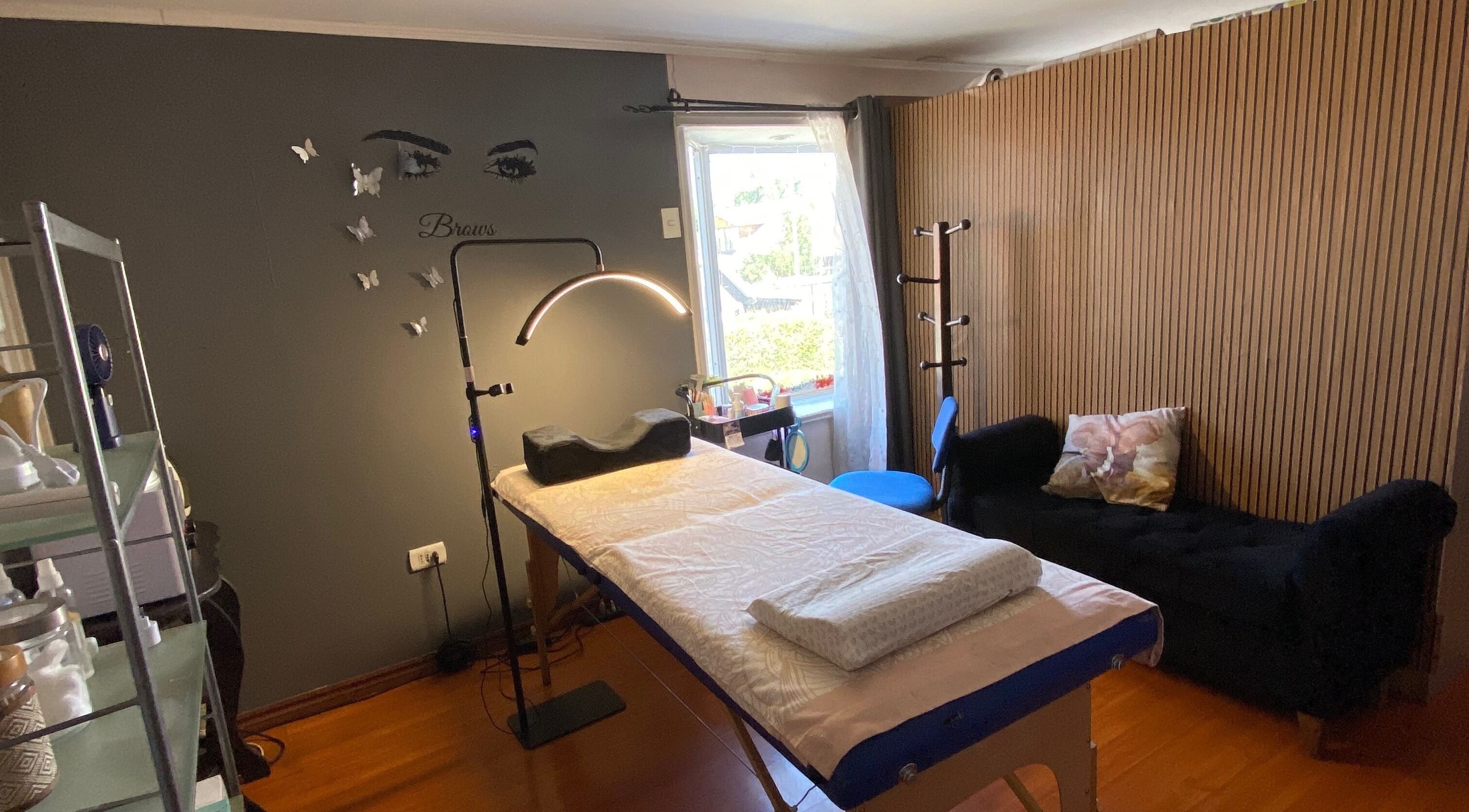 Interior acogedor del Centro estético Elyta’S, Región Metropolitana, CL. Sala con cama de tratamiento y decoraciones.