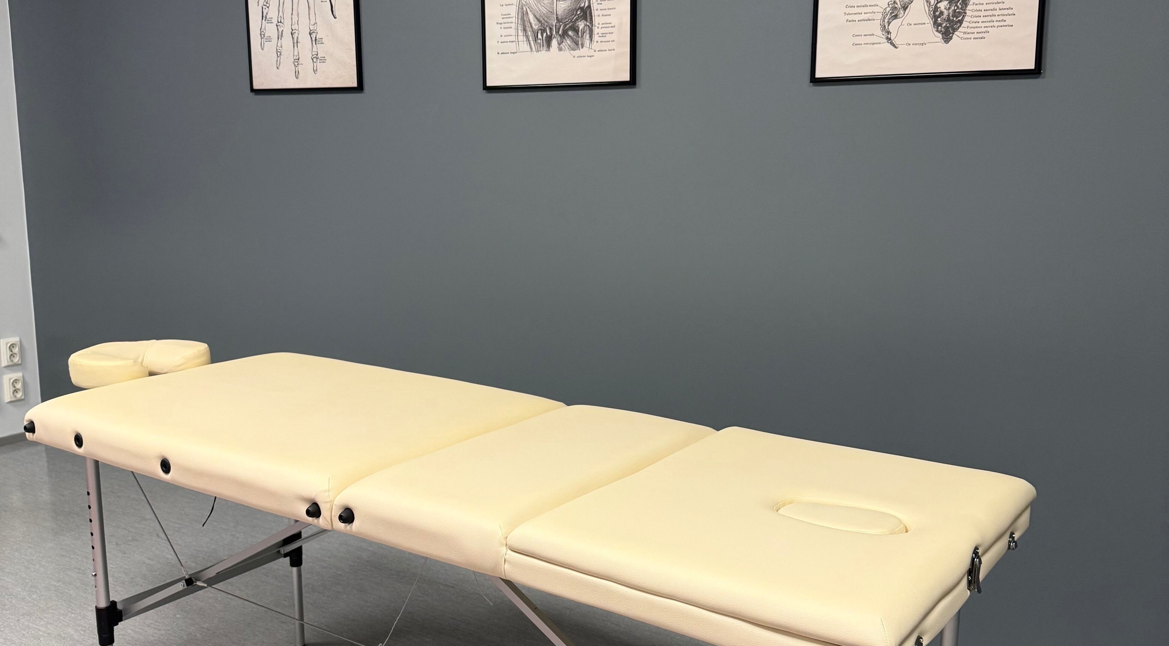 Massage table at Physio_tln, Tallinn, Harju maakond, EE with anatomical sketches on the wall.