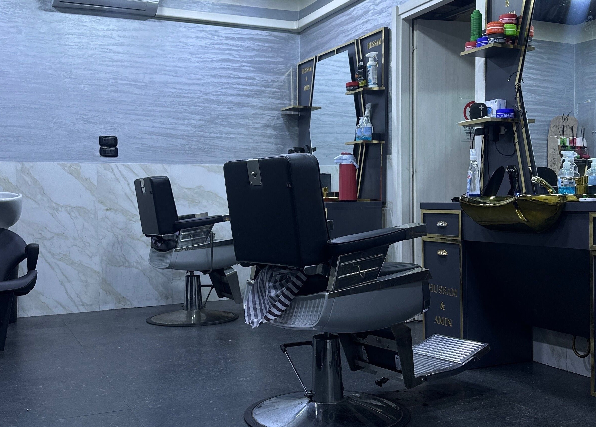 Sala moderna di BARBER HOSSY a Genova, Liguria, IT, con poltrone nere e lavandino elegante.