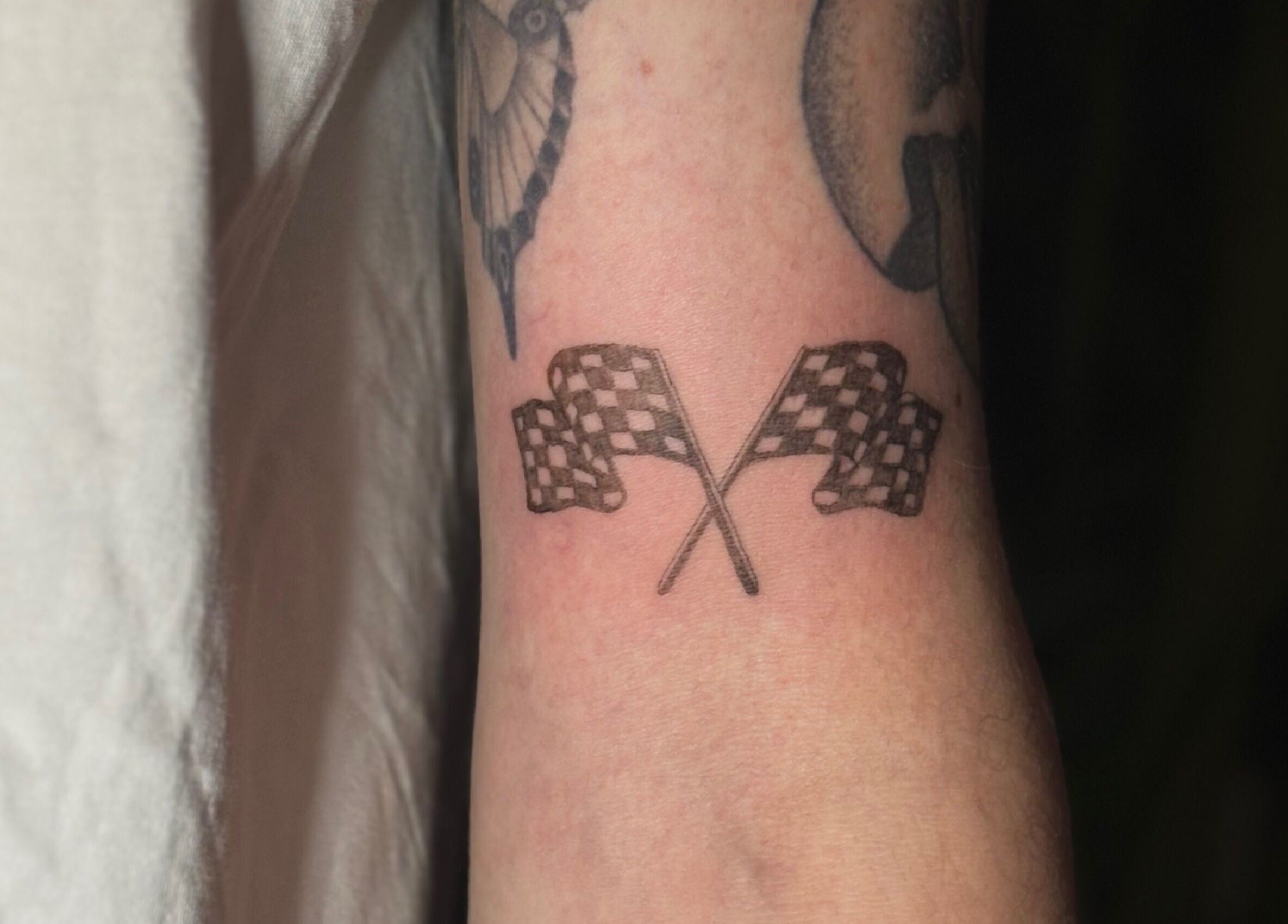 Arm tattoo of racing flags at Fine Little Things Studios, Bury St Edmund's, England, GB.