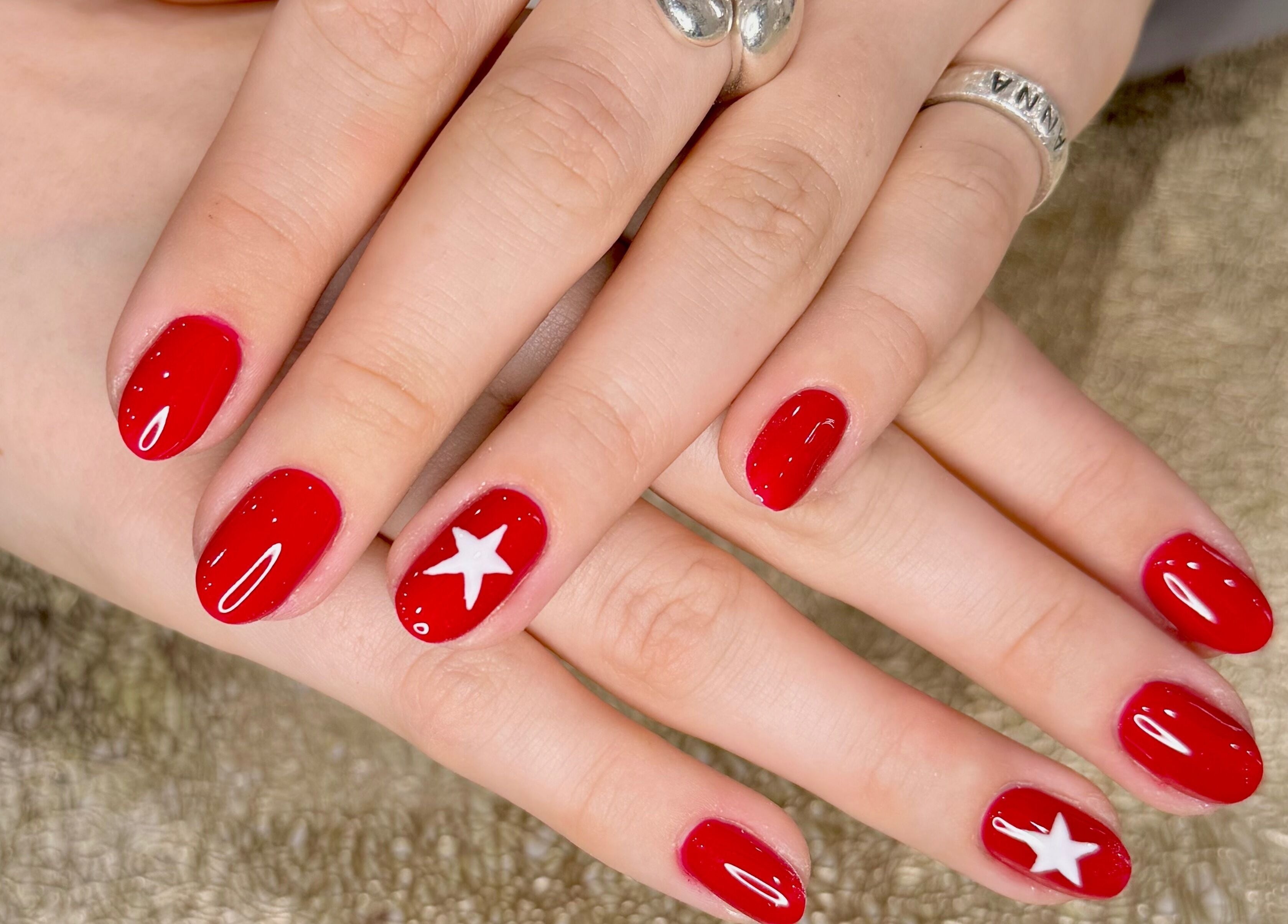 Elegant red nails with a white star design at Zara Nails, Kingston Upon Thames, England, GB.