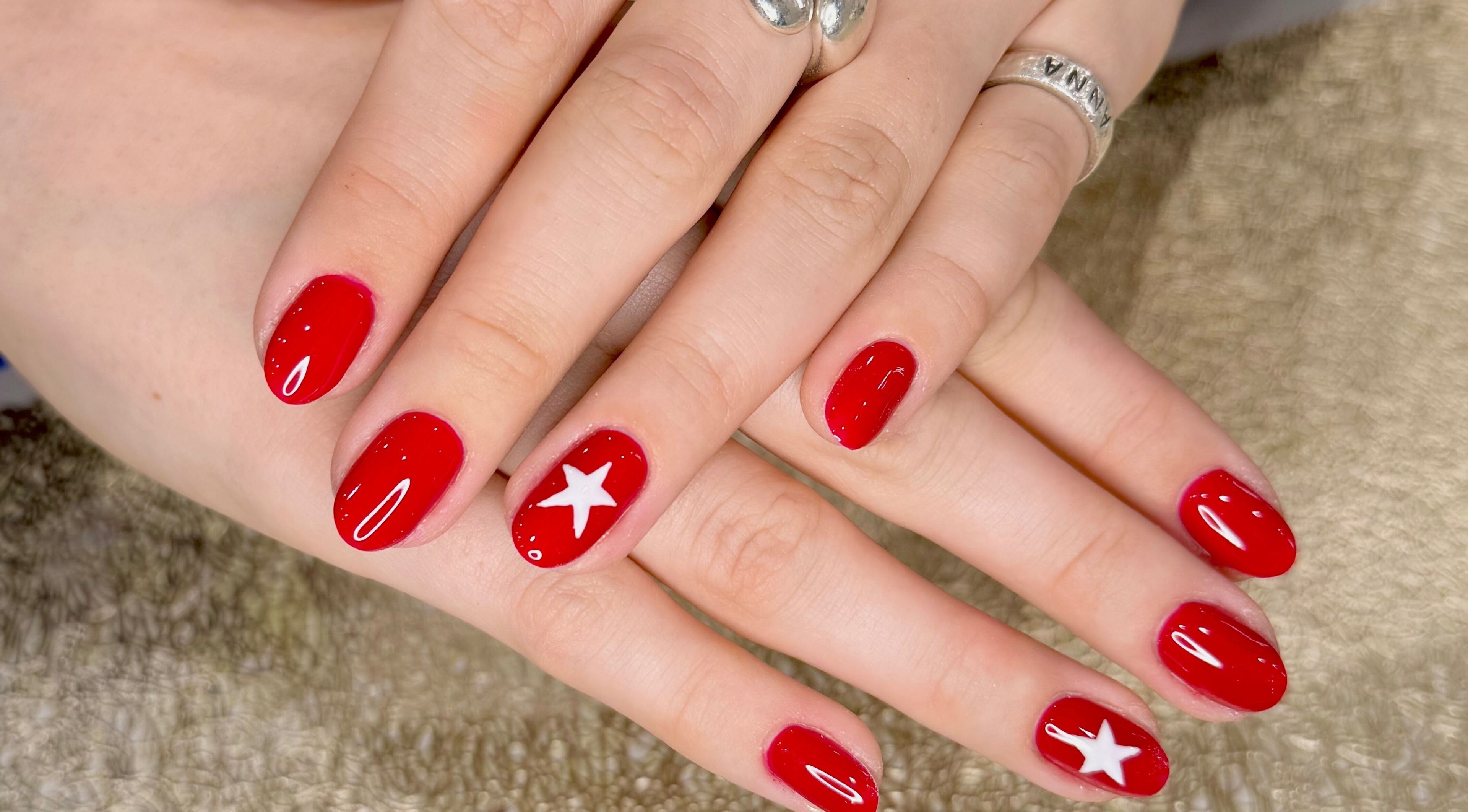 Elegant red nails with a white star design at Zara Nails, Kingston Upon Thames, England, GB.