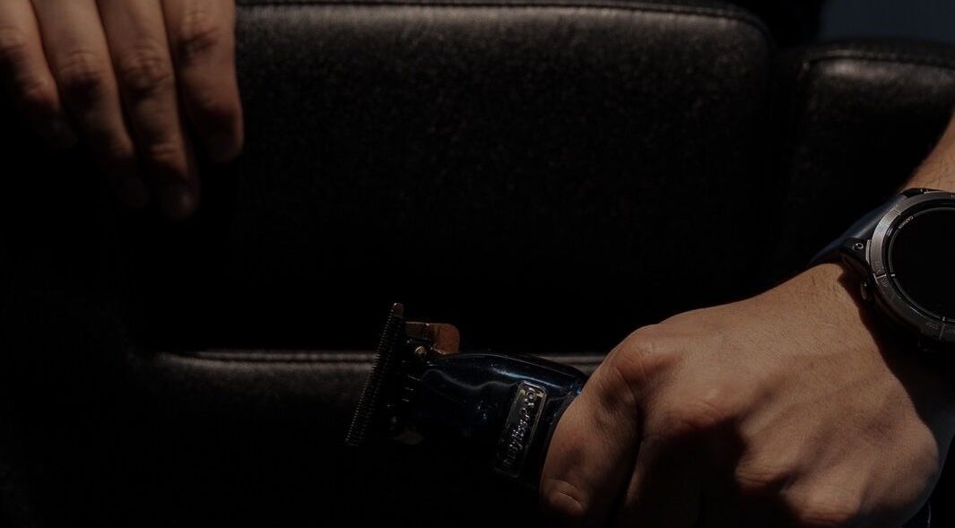 Close-up of a barber's hands with clippers at District Barber Society, Naucalpan De Juárez, Estado De México, MX.