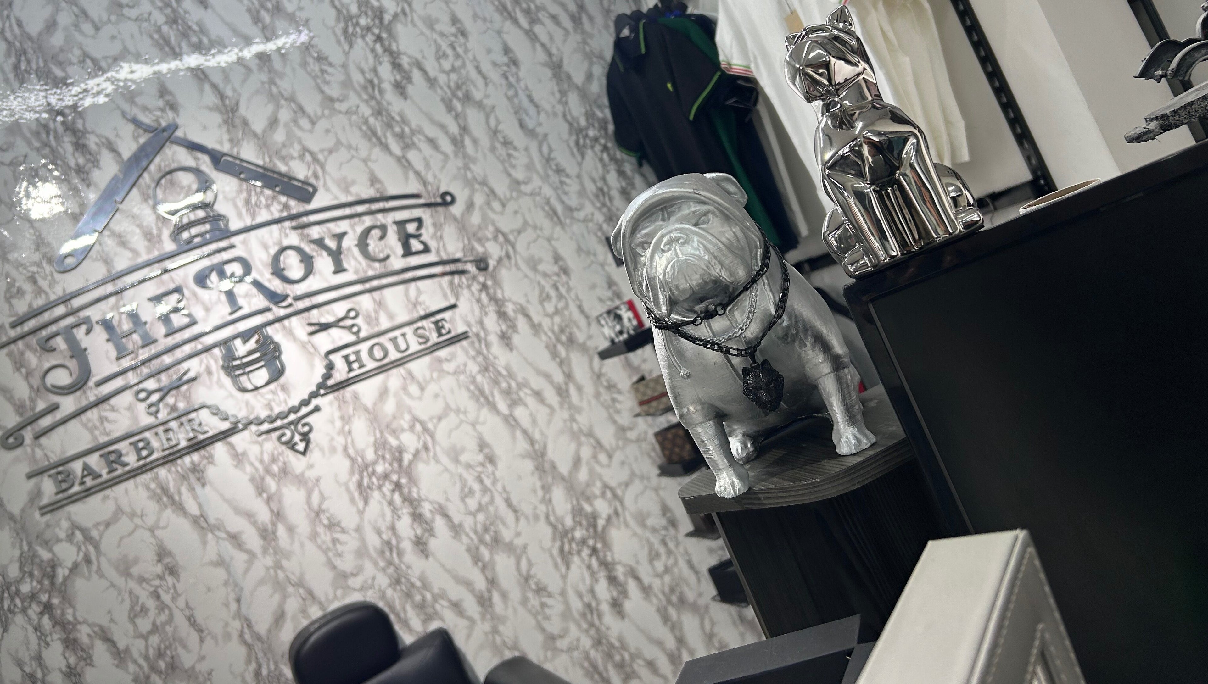 Decoración interior de The Royce Barber House en Bogotá, Bogotá, CO con estatuas y logo distintivo.