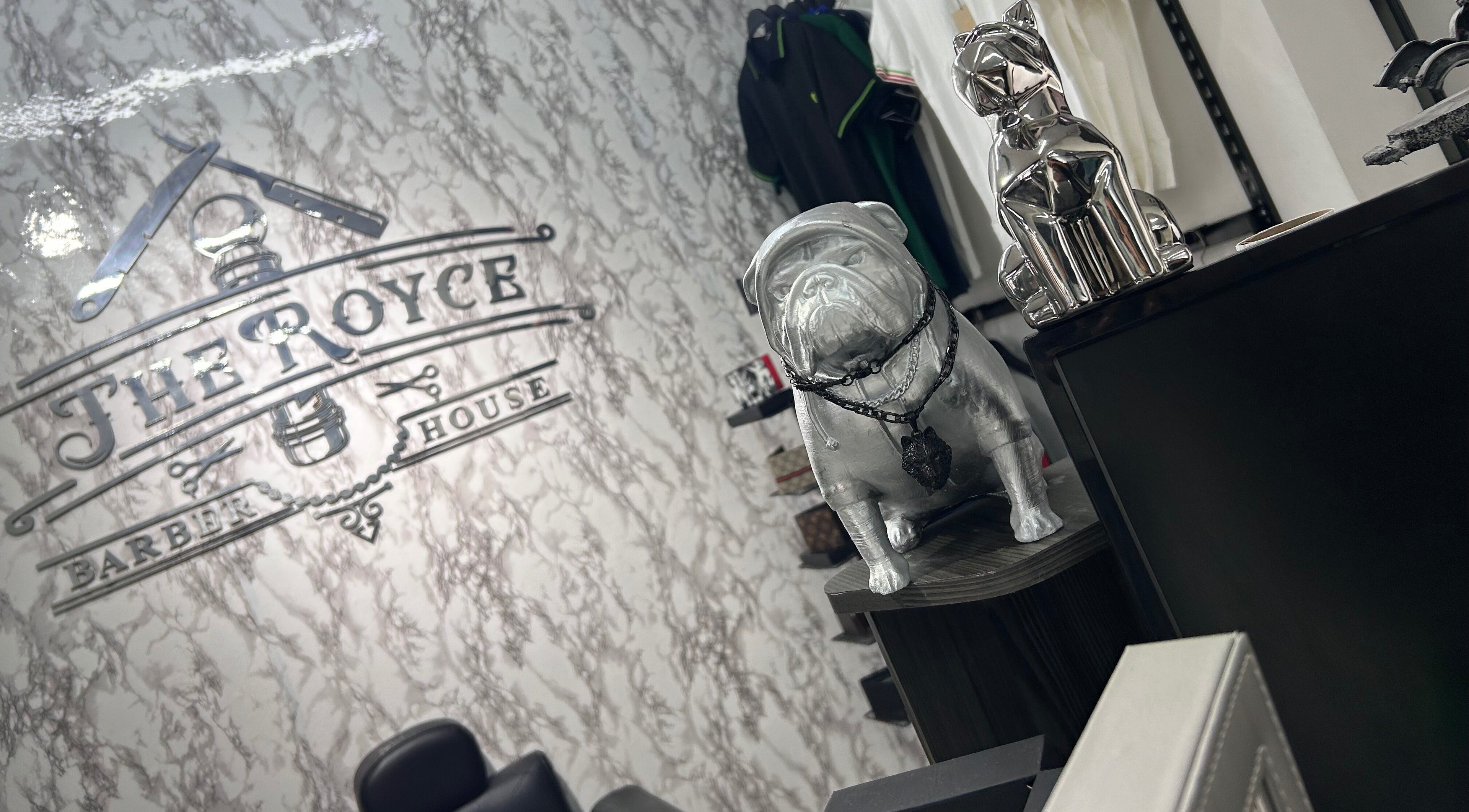 Decoración interior de The Royce Barber House en Bogotá, Bogotá, CO con estatuas y logo distintivo.