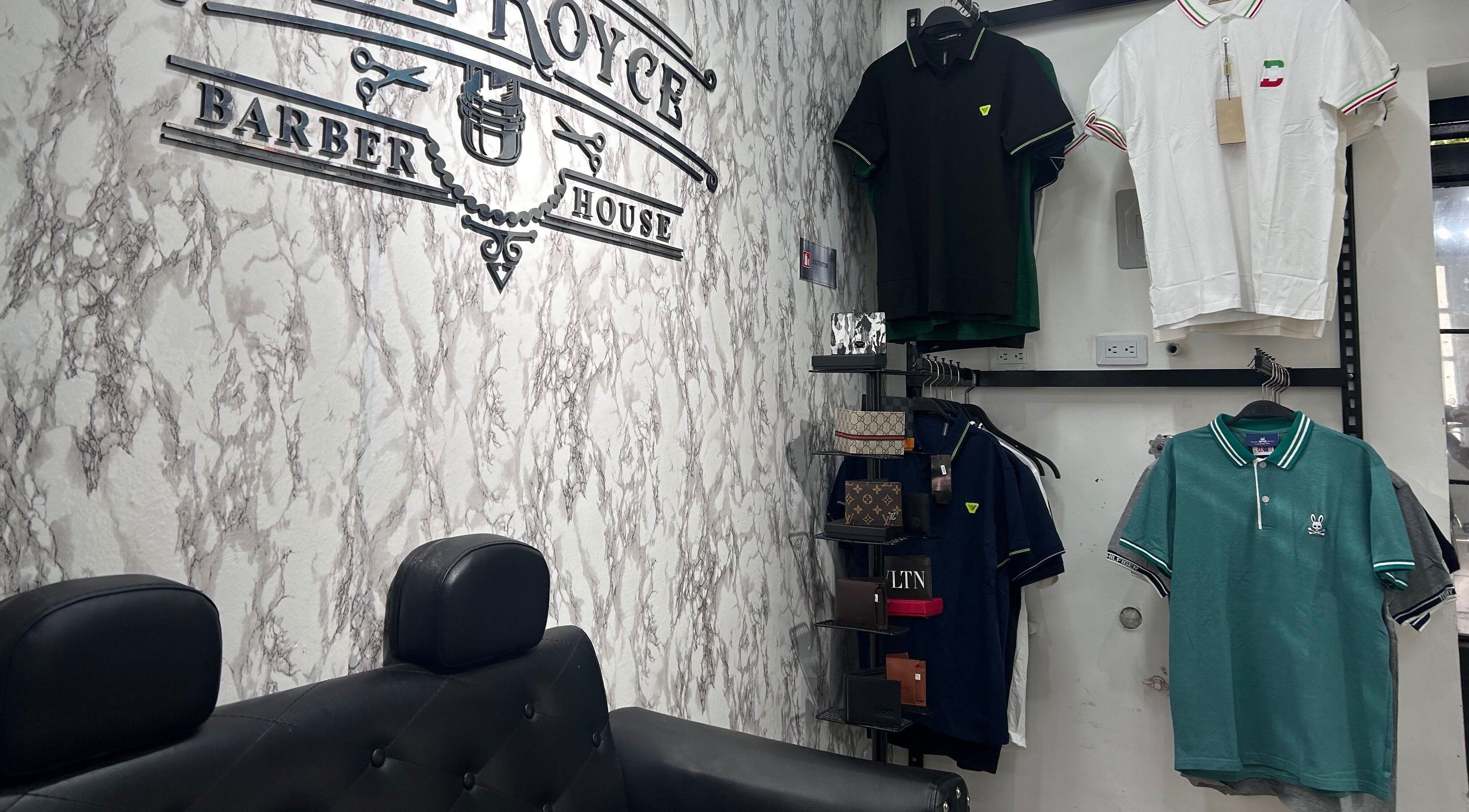 Interior de The Royce Barber House en Bogotá, Bogotá, CO con camisetas y sillón moderno.