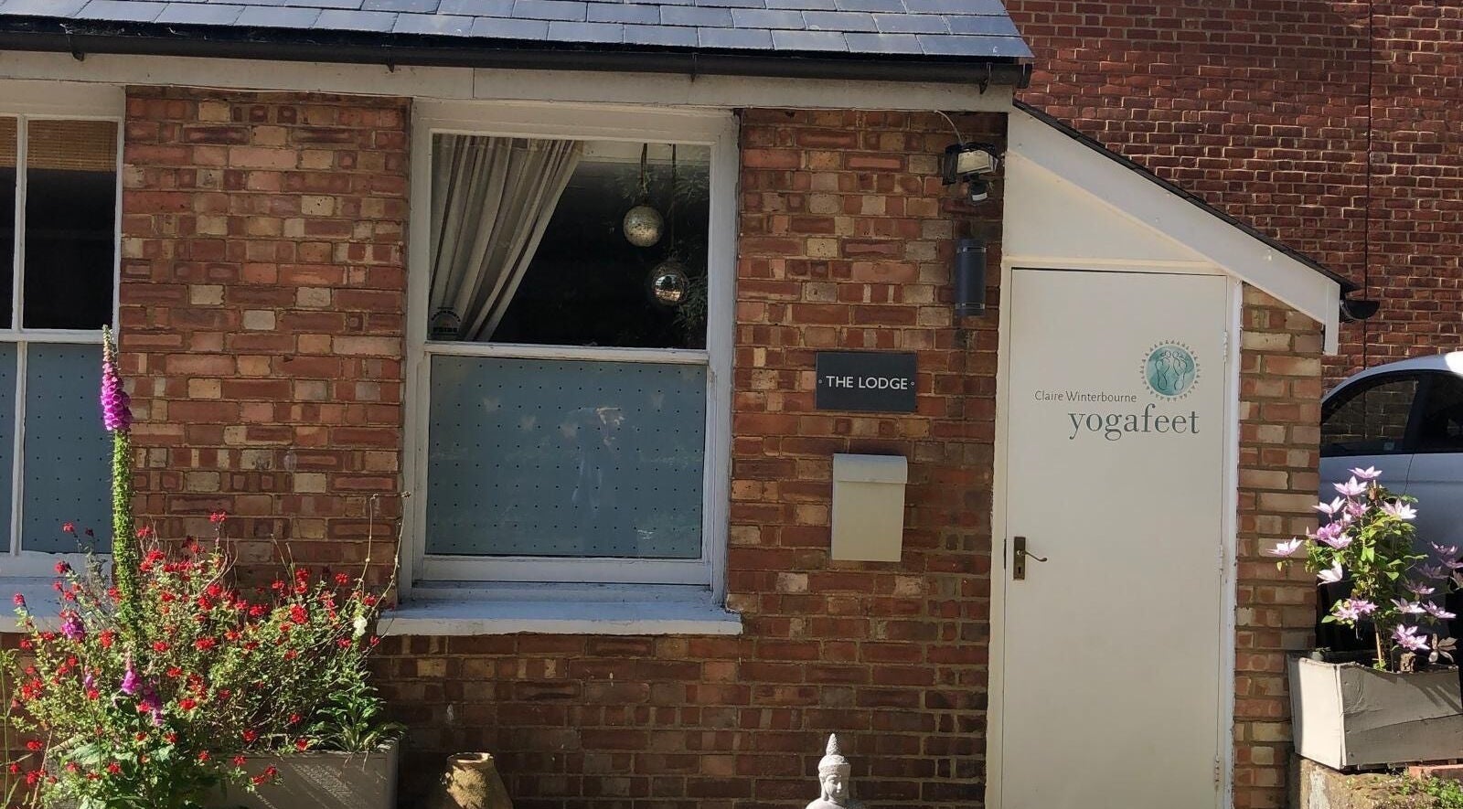 Entrance of Jess Clark Yoga Massage in Hitchin, England, GB with rustic brick facade and floral decor.