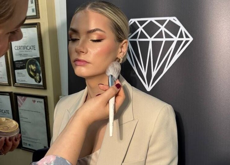 Makeup artist applies blush at Austeya Artistry Richmond, England, GB. Focus on expert technique and glowing skin.