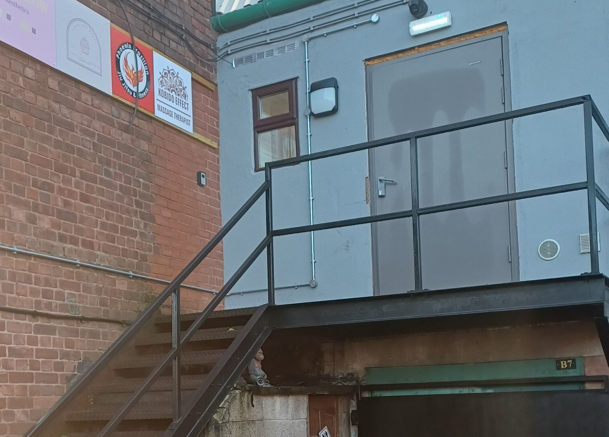 Tylne wejście do Kobido Effect w Mansfield, England, GB, widoczne schody prowadzące do szarego budynku.