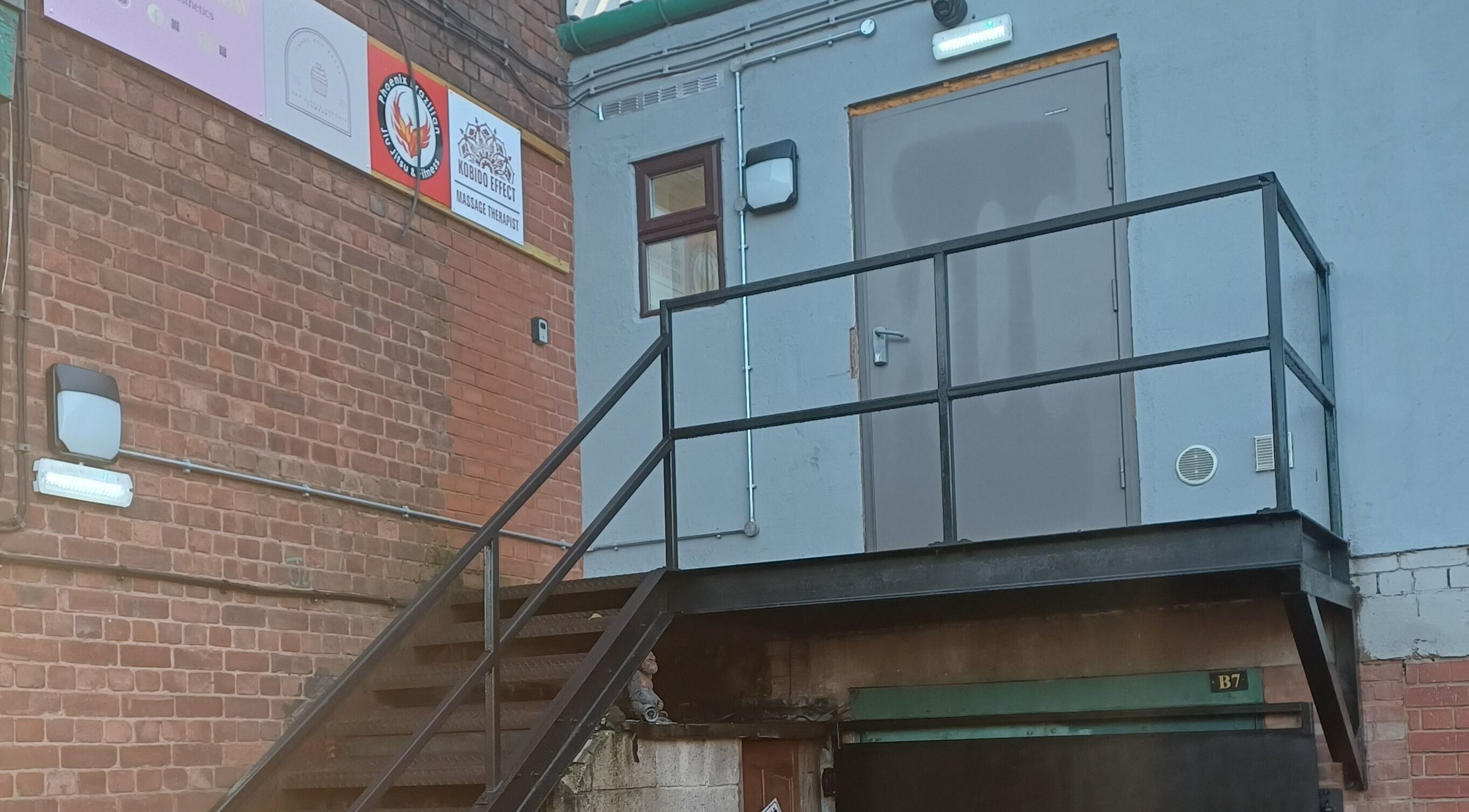 Tylne wejście do Kobido Effect w Mansfield, England, GB, widoczne schody prowadzące do szarego budynku.