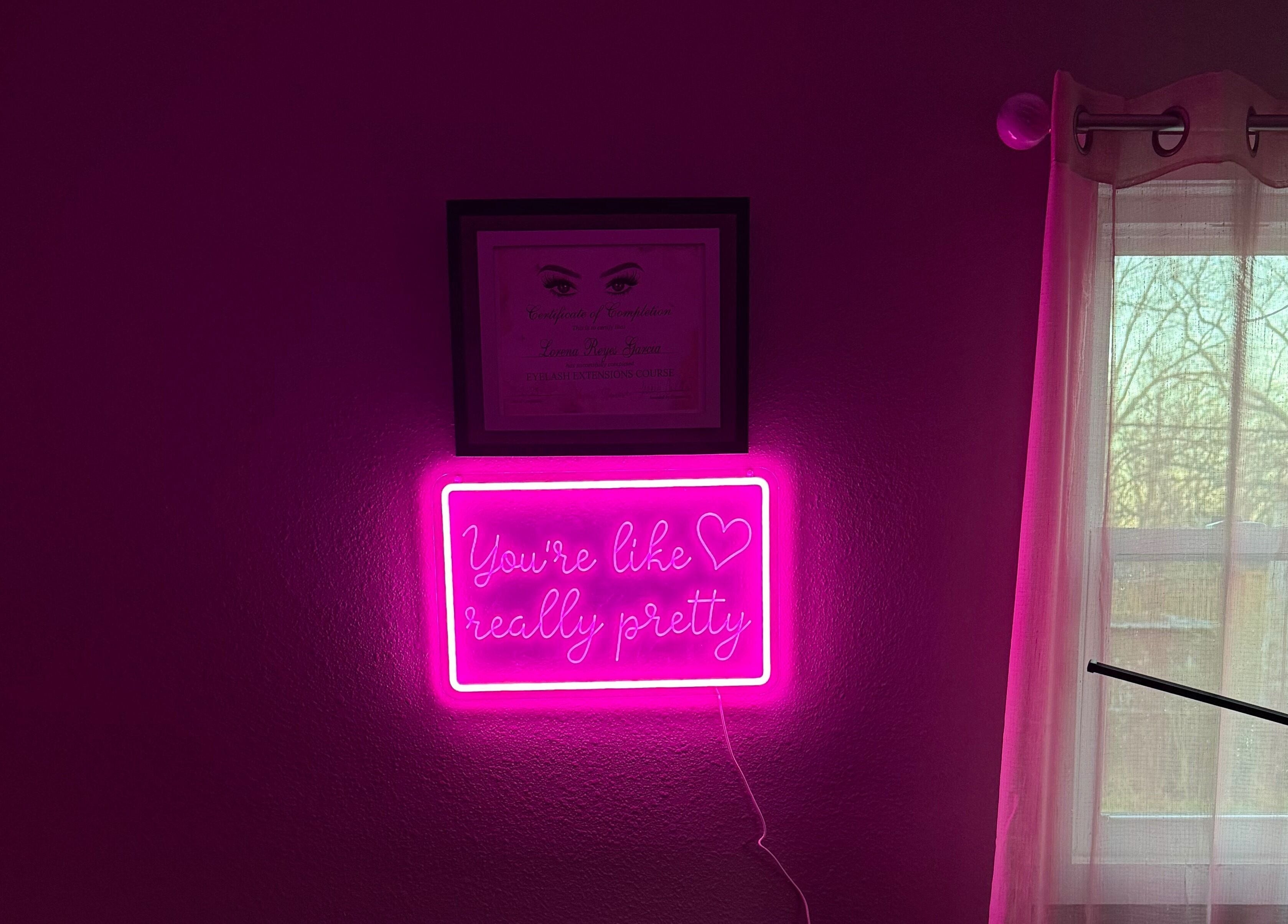 Neon sign in Luxe Encanto Studio LLC, Gadsden, Alabama, US, reads 'You're like really pretty' beside a window.