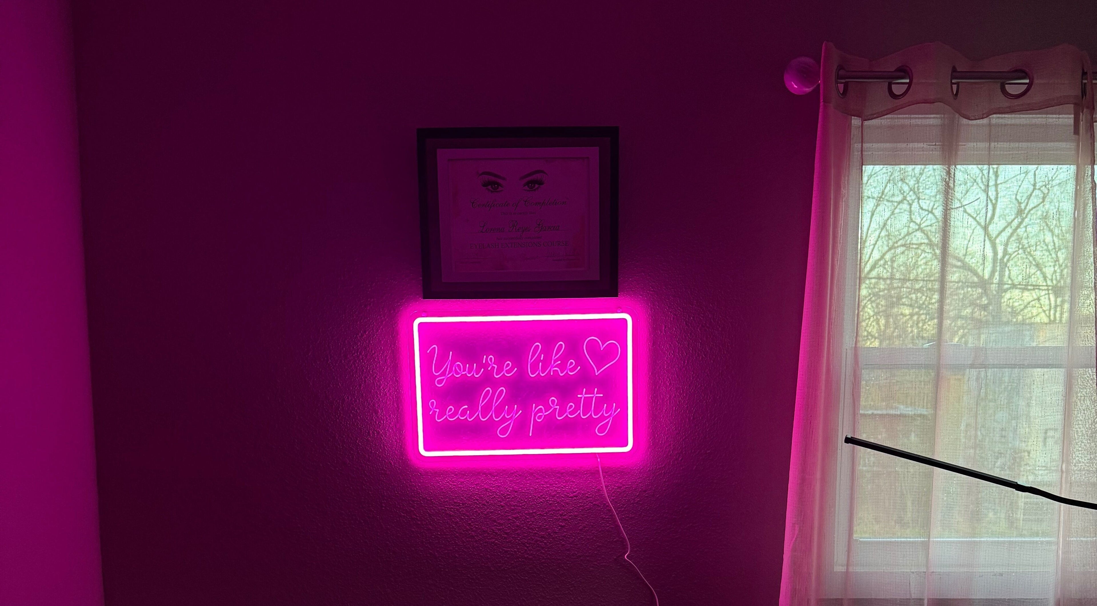 Neon sign in Luxe Encanto Studio LLC, Gadsden, Alabama, US, reads 'You're like really pretty' beside a window.