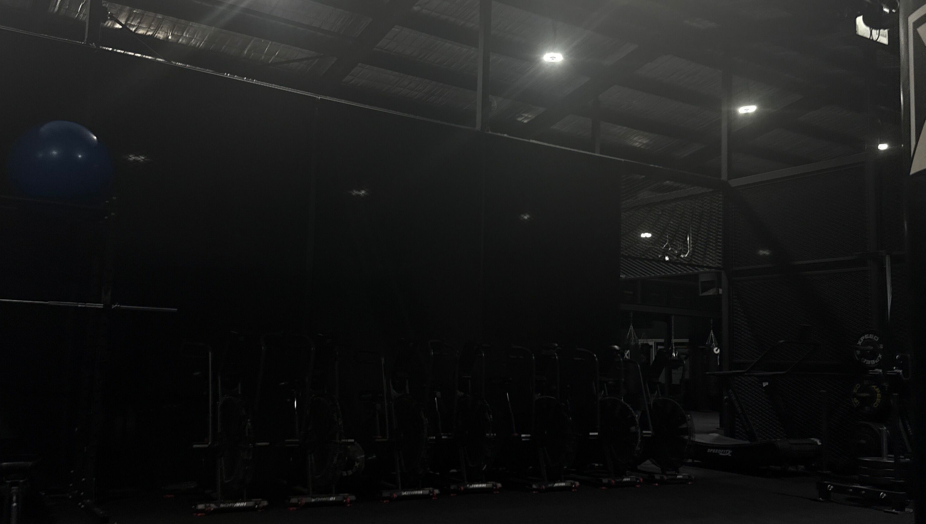Dimly lit gym area at Team Igusti in Hindmarsh, South Australia, AU featuring exercise equipment.