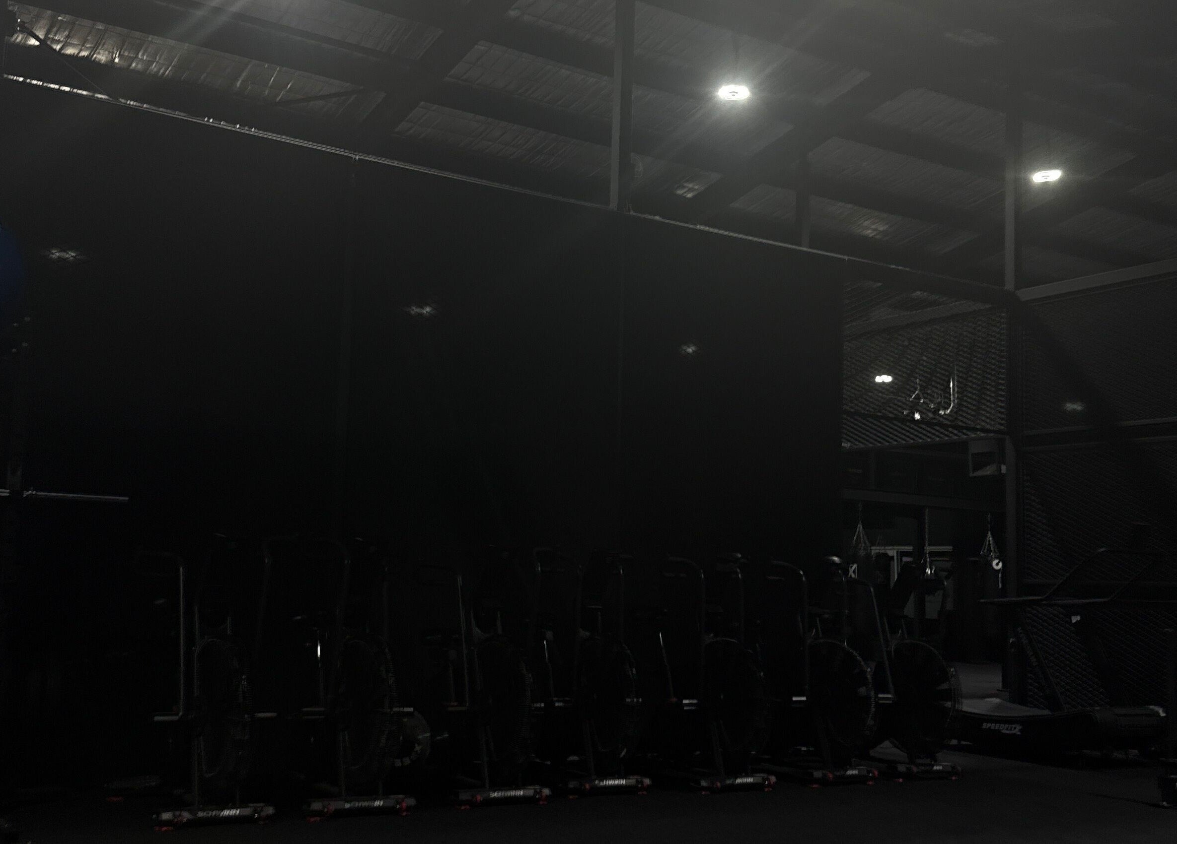 Dimly lit gym area at Team Igusti in Hindmarsh, South Australia, AU featuring exercise equipment.