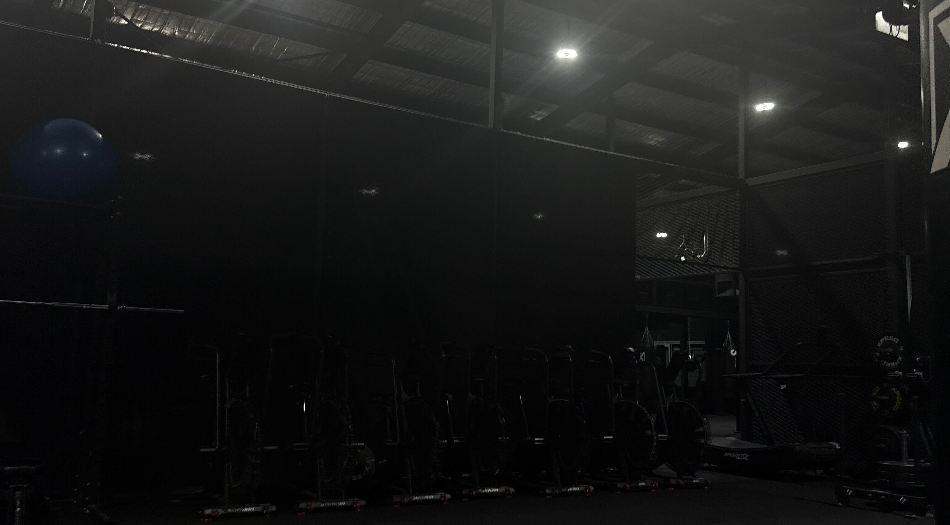 Dimly lit gym area at Team Igusti in Hindmarsh, South Australia, AU featuring exercise equipment.
