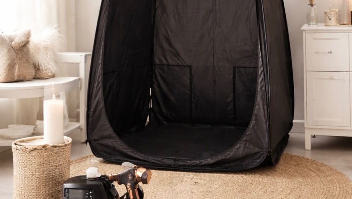 Spray tanning setup at Golden Edit in Surrey, British Columbia, CA, featuring a sleek black tent and cozy decor.