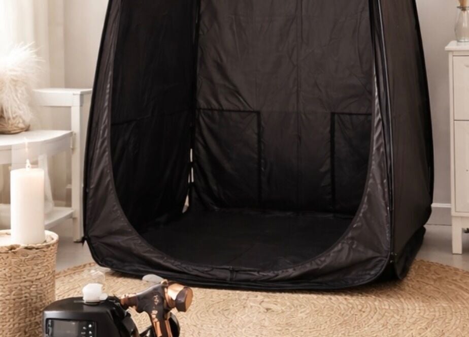Spray tanning setup at Golden Edit in Surrey, British Columbia, CA, featuring a sleek black tent and cozy decor.